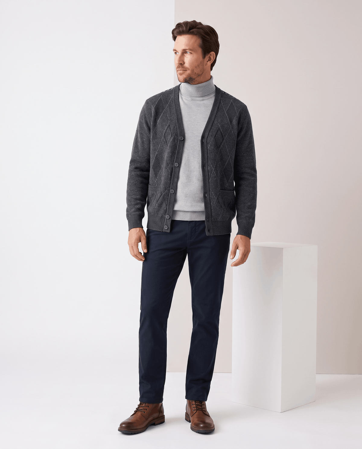 Full-length view of the dark gray cardigan open over a gray turtleneck and navy trousers