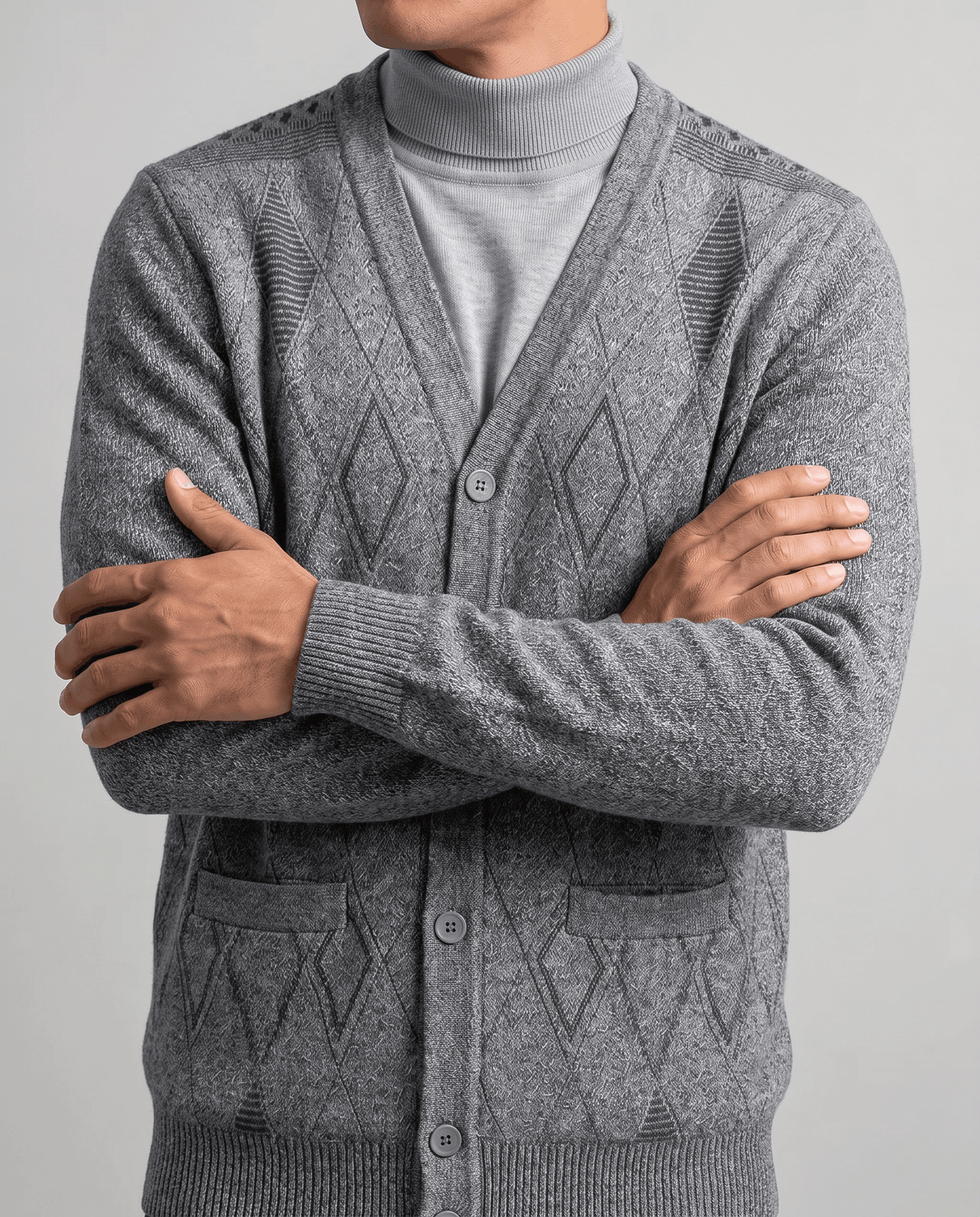 Arms crossed in a light gray marled cardigan showing buttons and a patch pocket