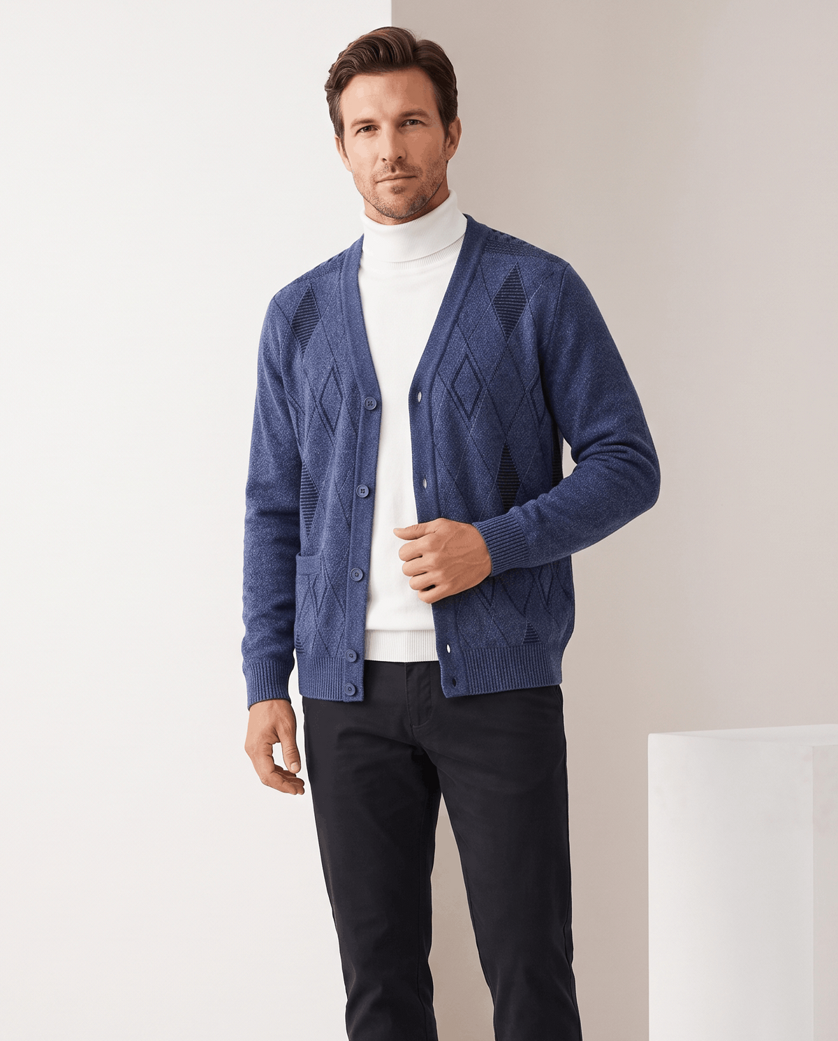 Man wearing a navy argyle V-neck cardigan sweater open over a white turtleneck