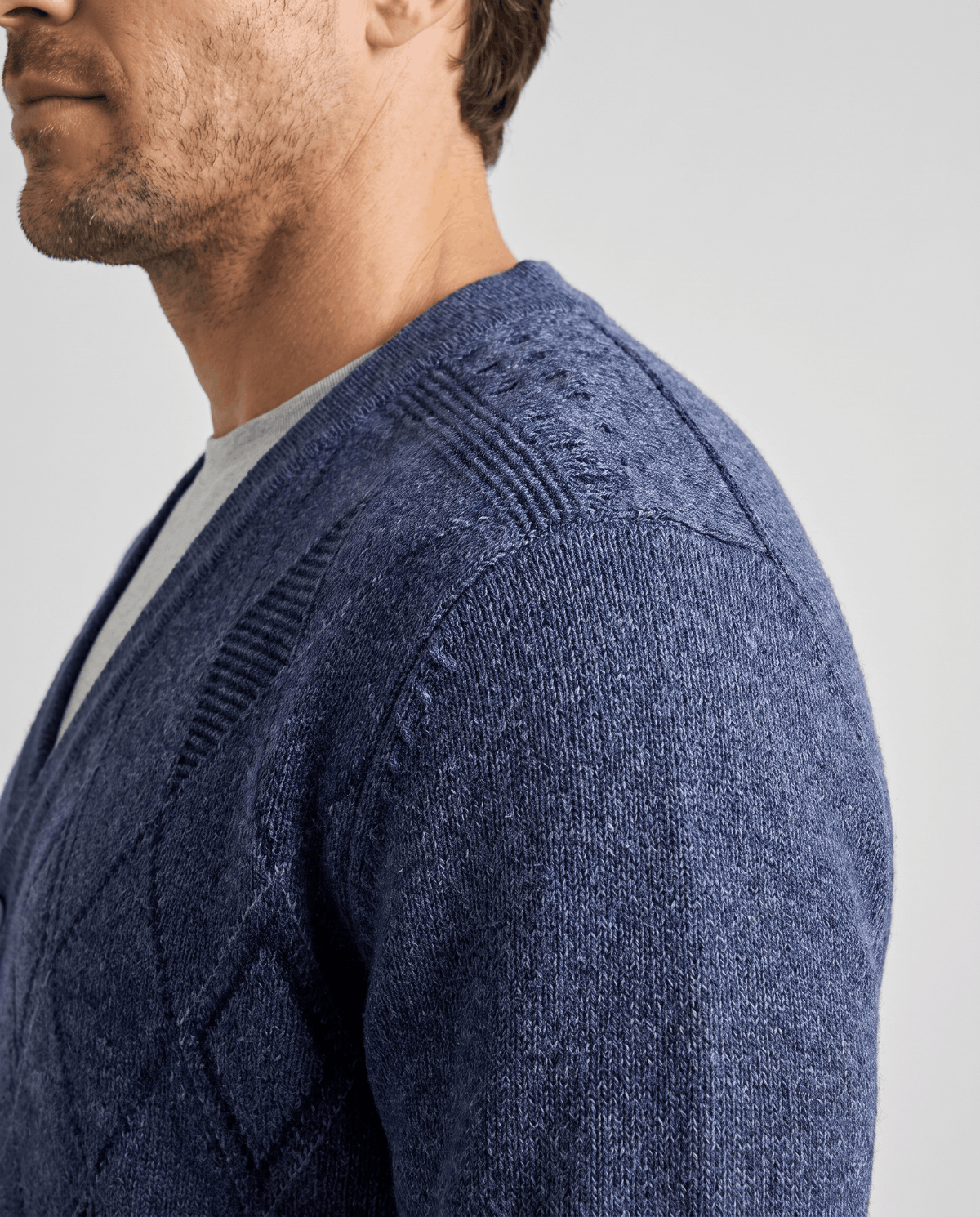 Side profile of the navy cardigan showing the V-neck and textured shoulder knit