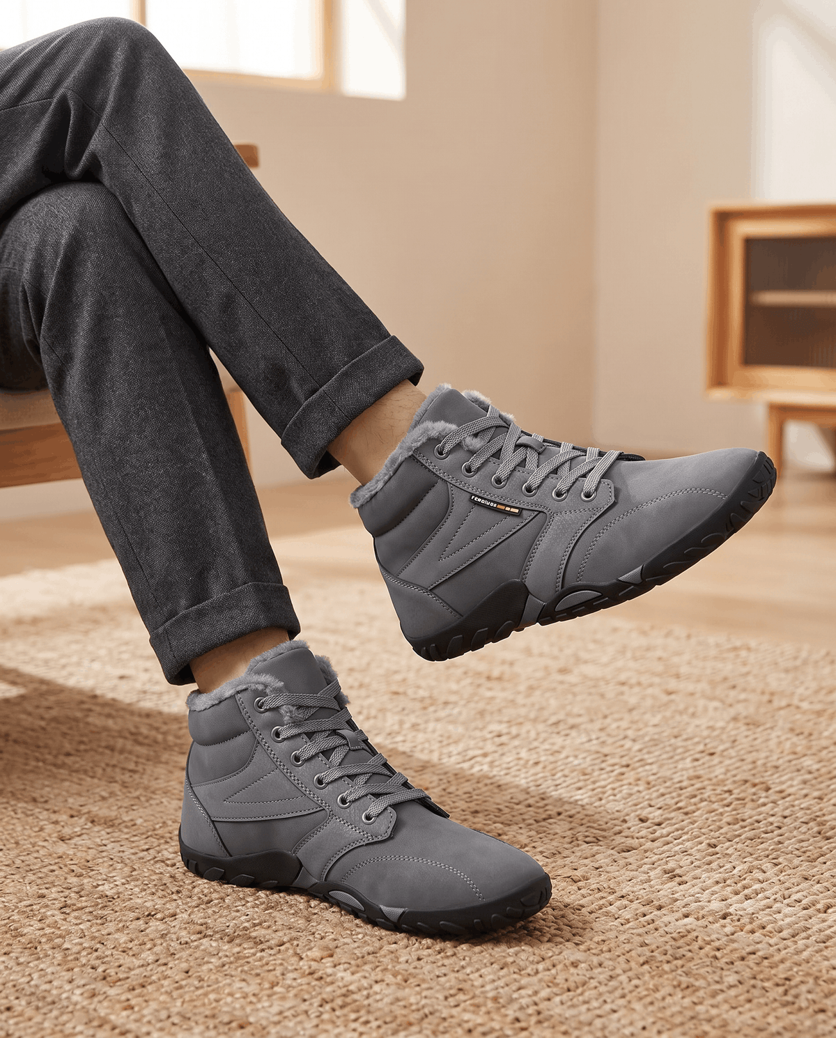 Gray boots worn with charcoal trousers, one heel lifted mid-step indoors
