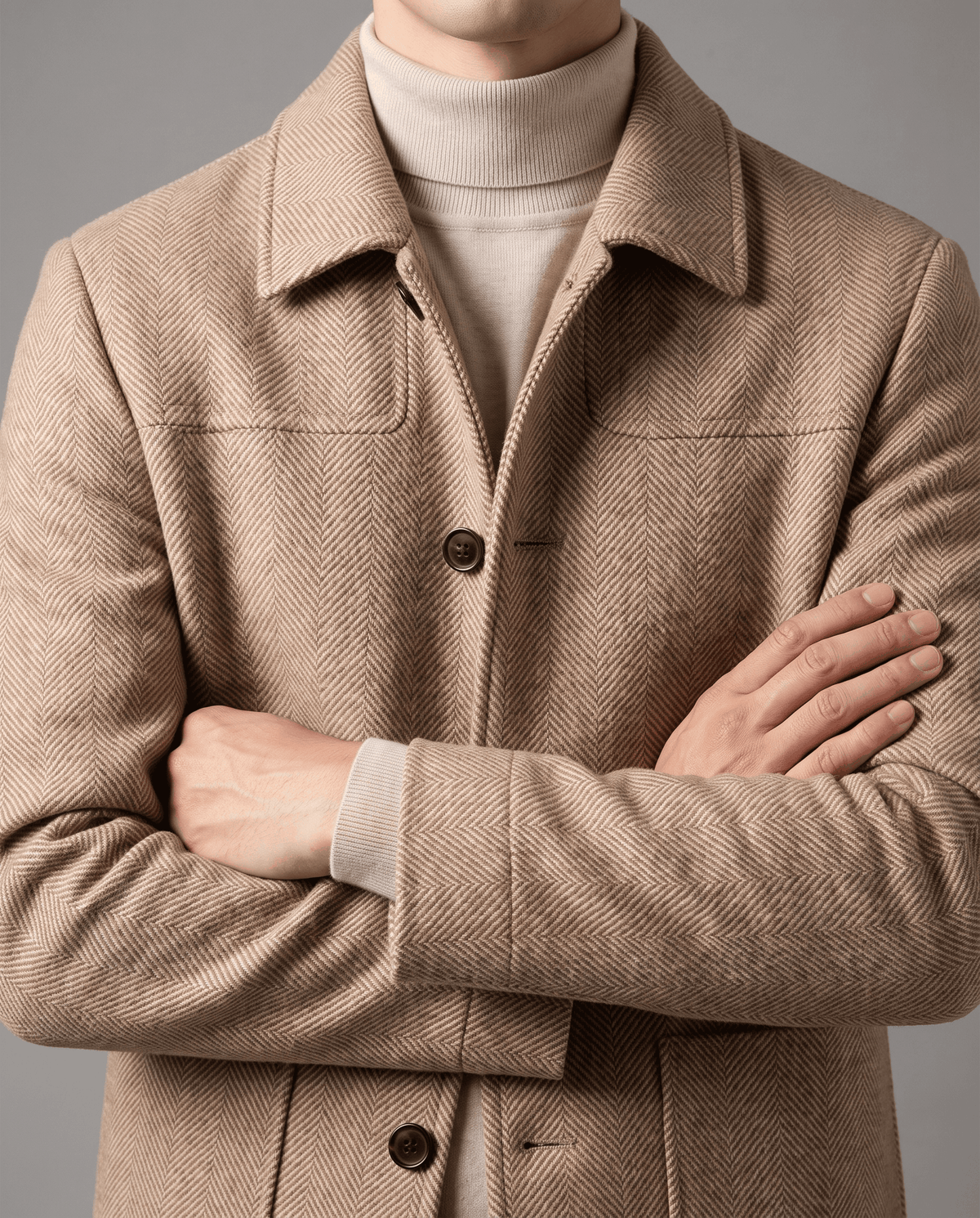 Collar and button front of the Henrik beige herringbone wool coat, arms crossed