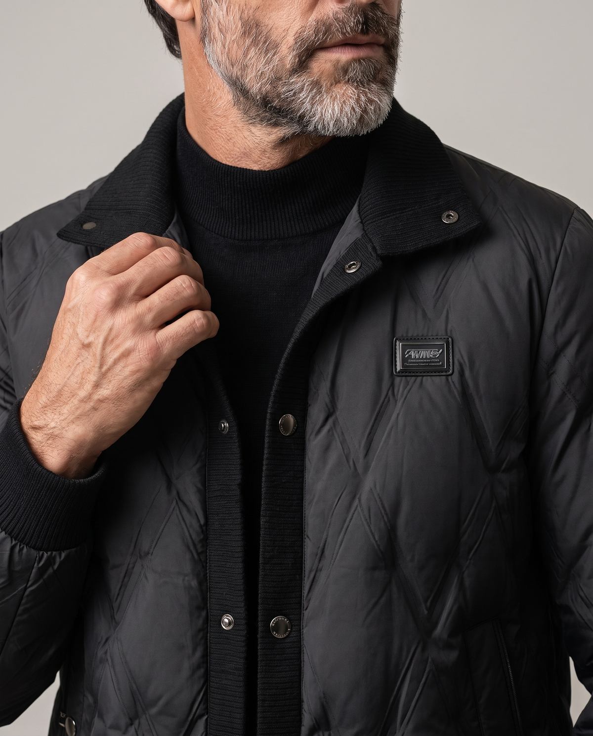Man touching the snap-button front of a black diamond quilted puffer jacket