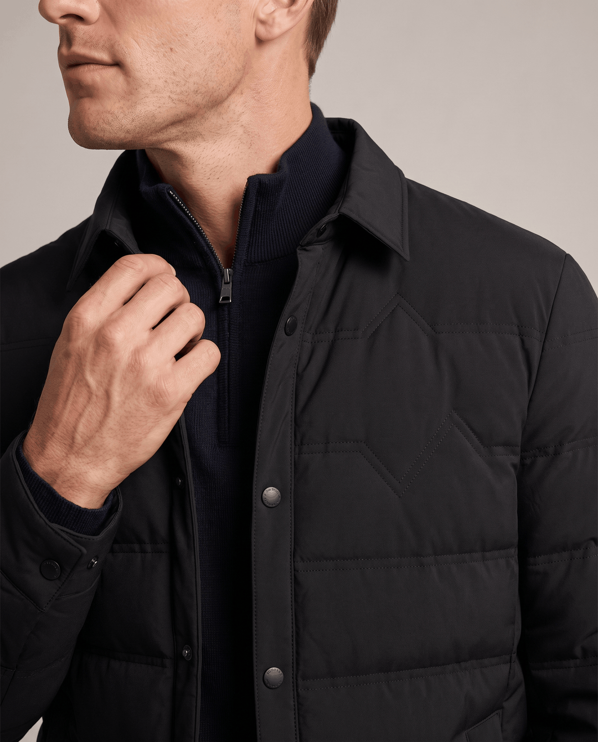 Close-up of the point collar and snap placket on a black puffer jacket