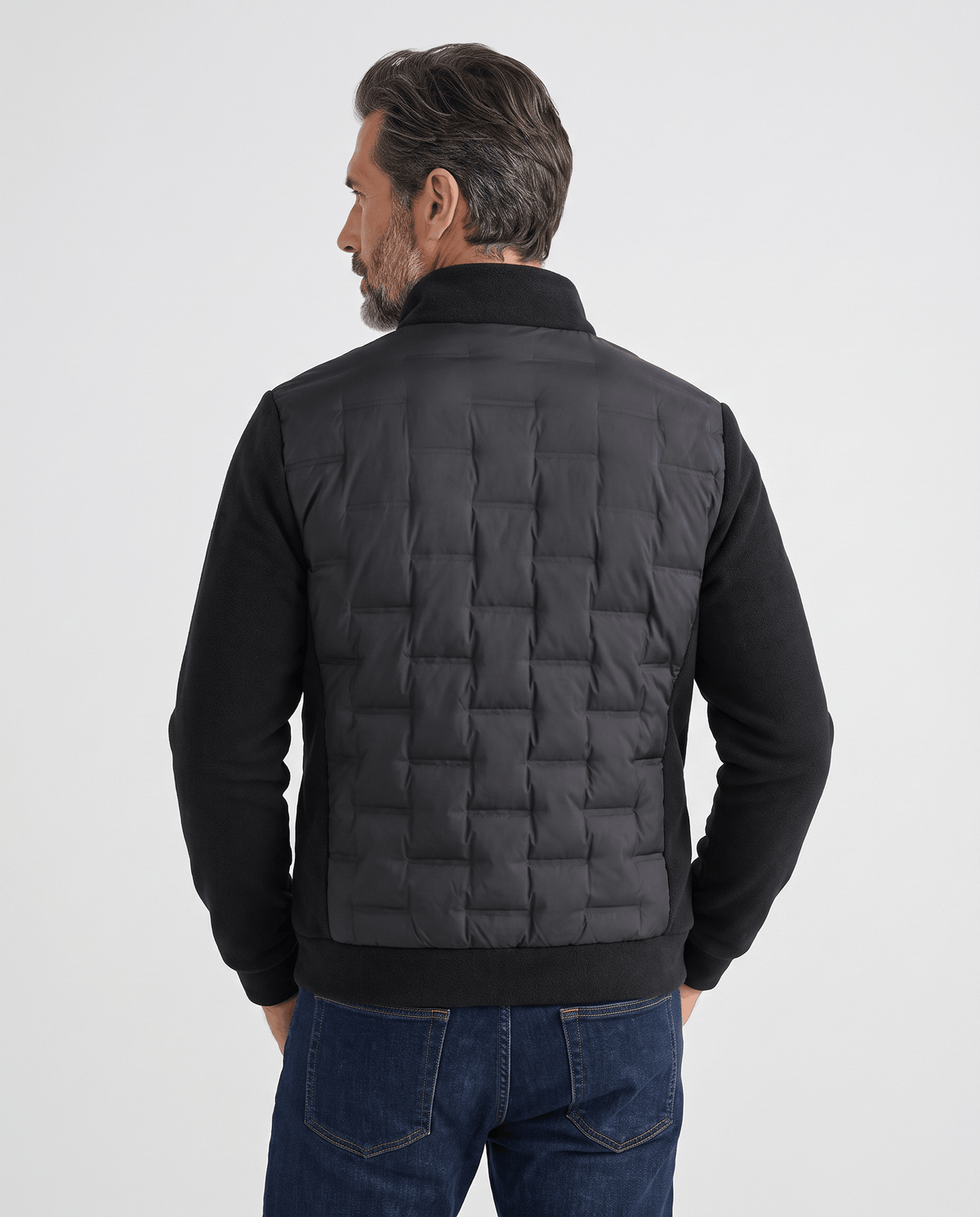 Back view of a man wearing a black quilted hybrid puffer jacket with stand collar
