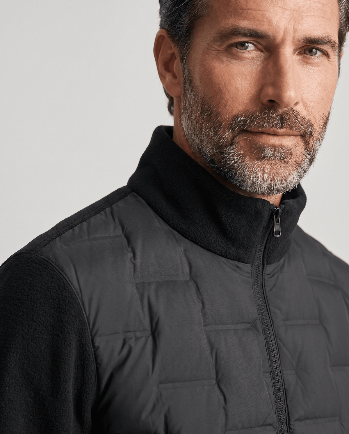 Close-up of the stand collar and quilted front on a black hybrid puffer jacket