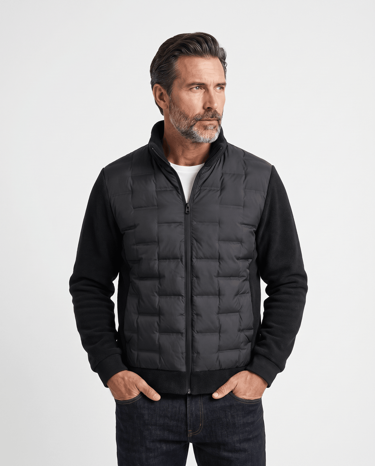 Man wearing a black hybrid puffer jacket with quilted body and fleece sleeves, front view
