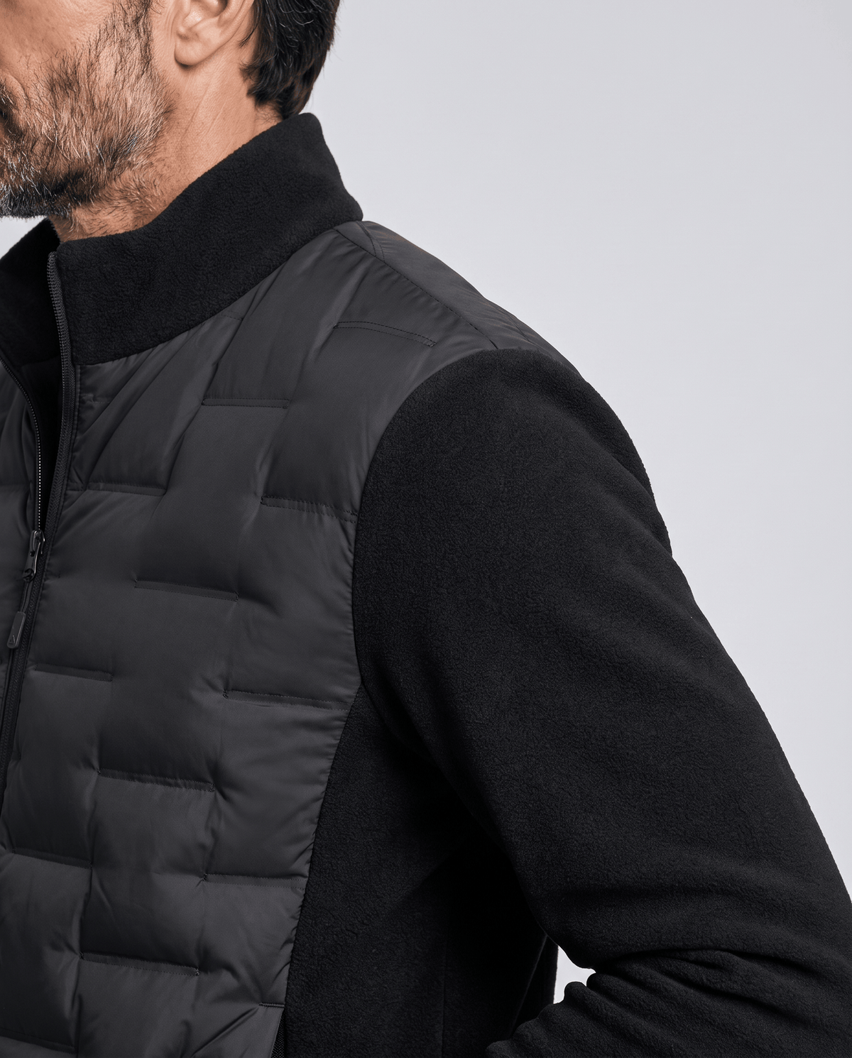 Close-up of the quilted panel meeting the fleece sleeve on a black puffer jacket