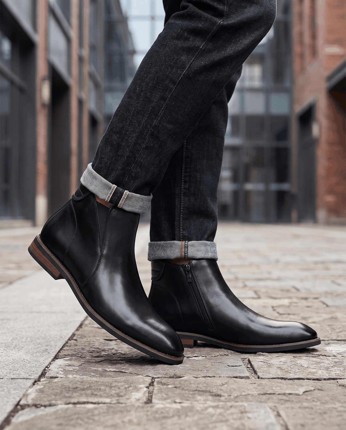Man wearing black Chelsea boots with dark trousers on a brick street