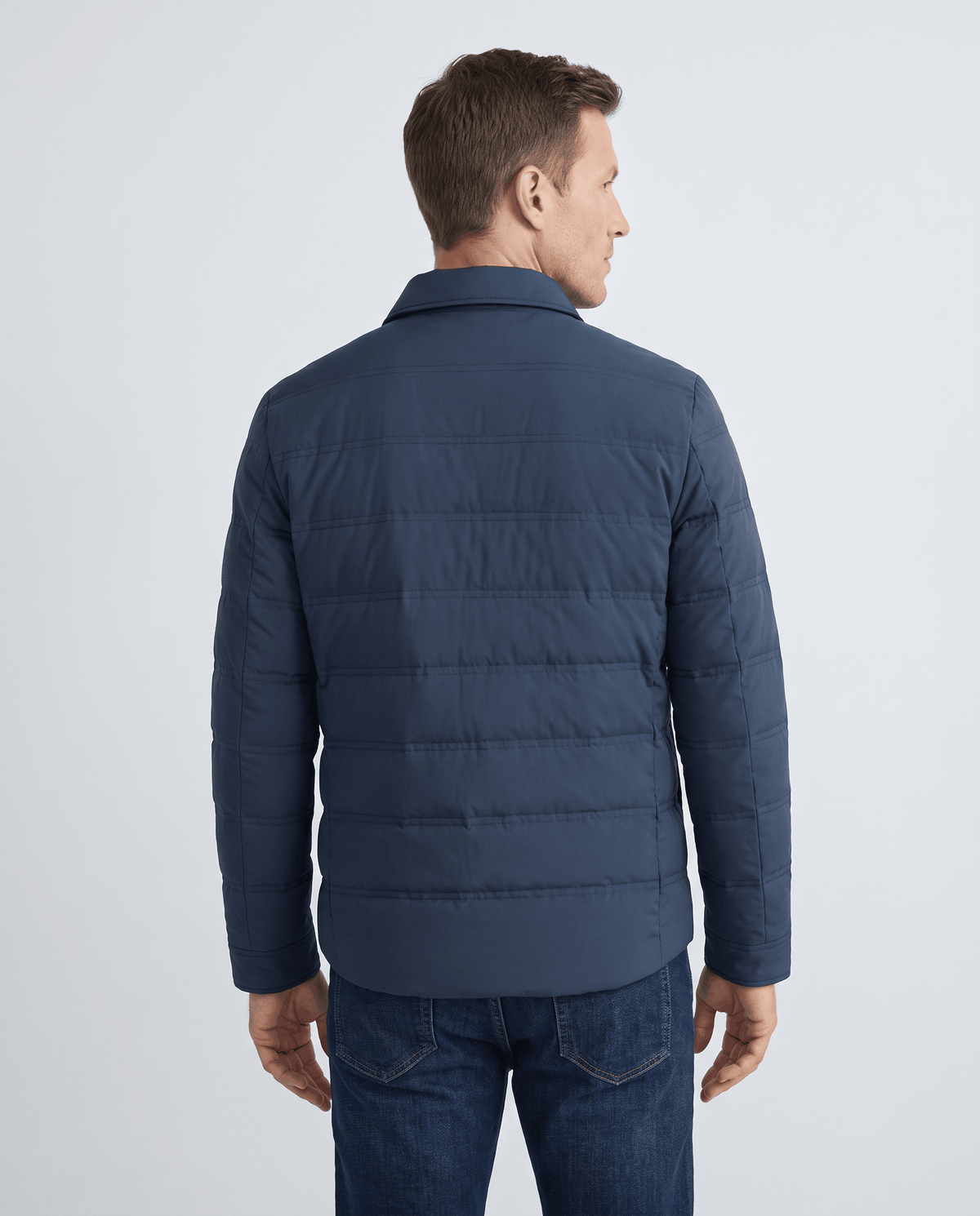 Back view of a man wearing a blue quilted puffer jacket
