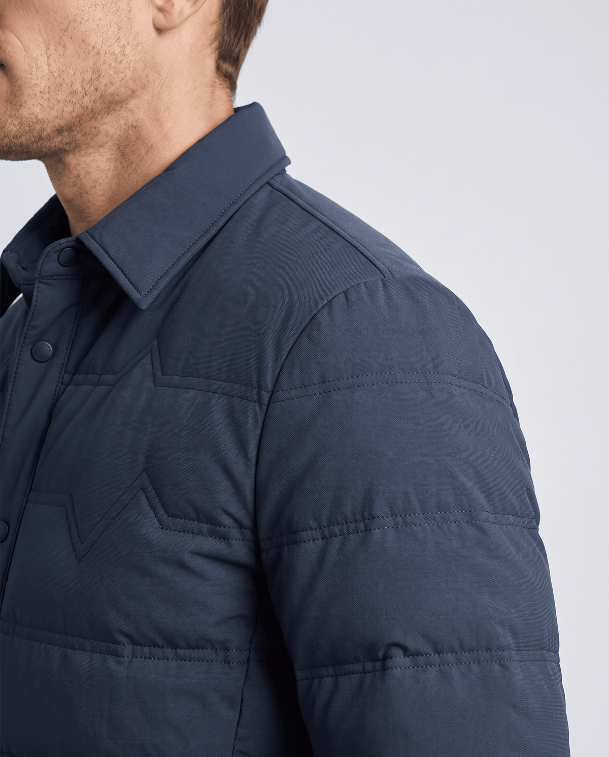 Close-up of the quilted shoulder and sleeve on a blue puffer jacket