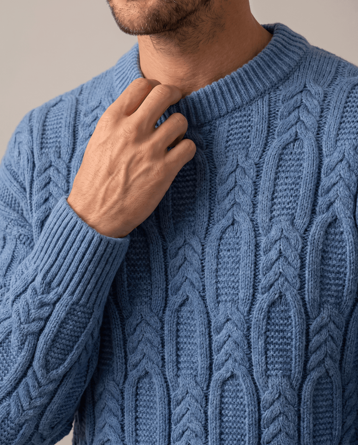 Close-up of hand at the ribbed collar of a blue braided knit