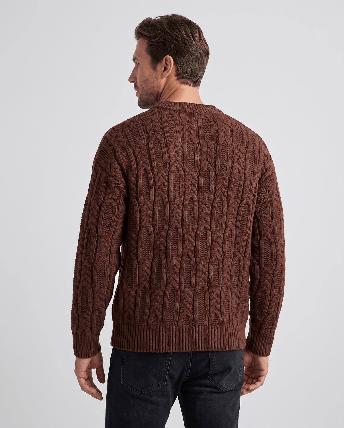 Back view of brown cable pullover with ribbed hem and dark jeans