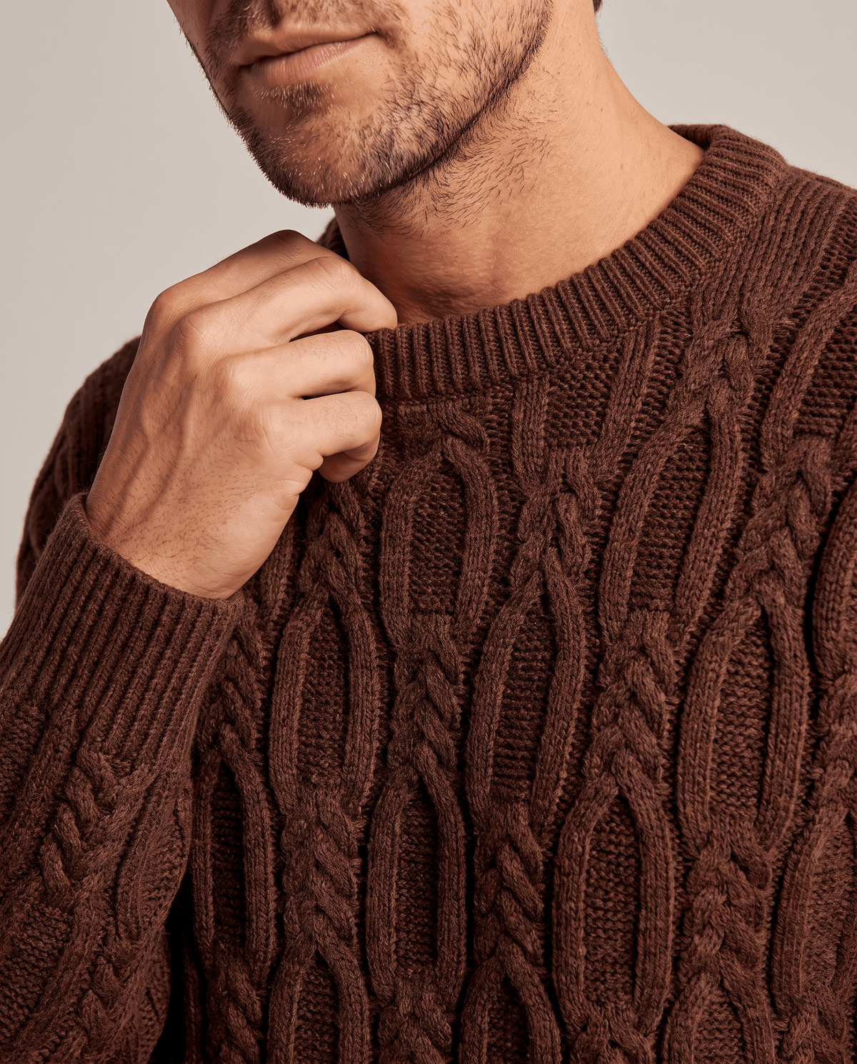 Close-up of hand at the ribbed collar of a brown chunky knit