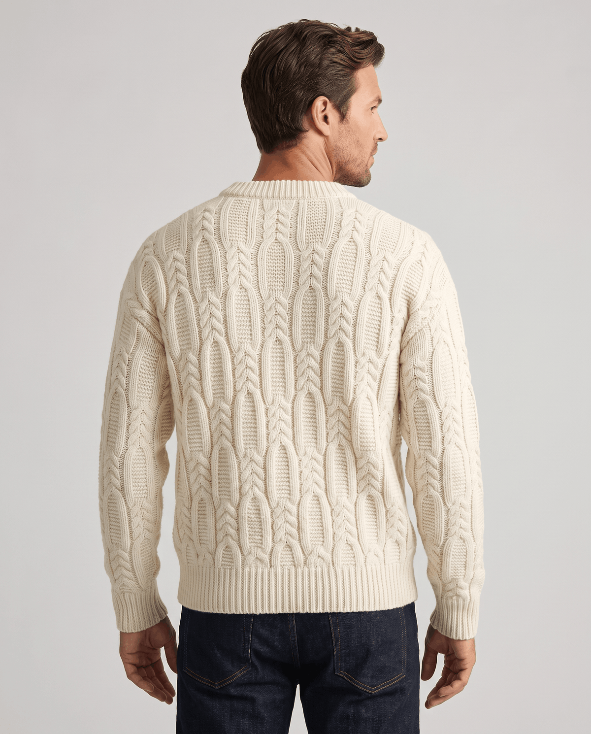 Back view of cream cable sweater with ribbed hem