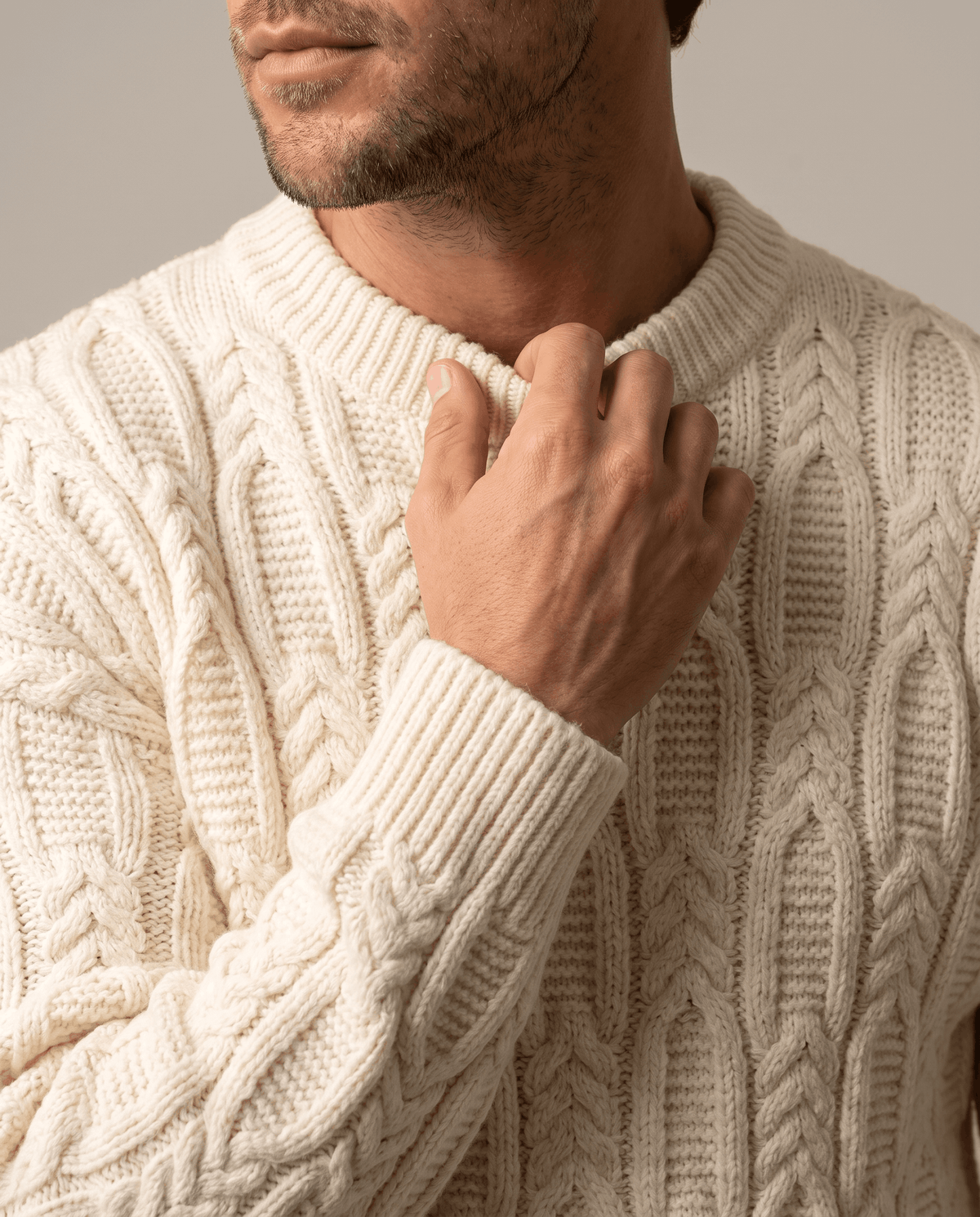 Close-up of hand at the ribbed collar of a cream chunky knit