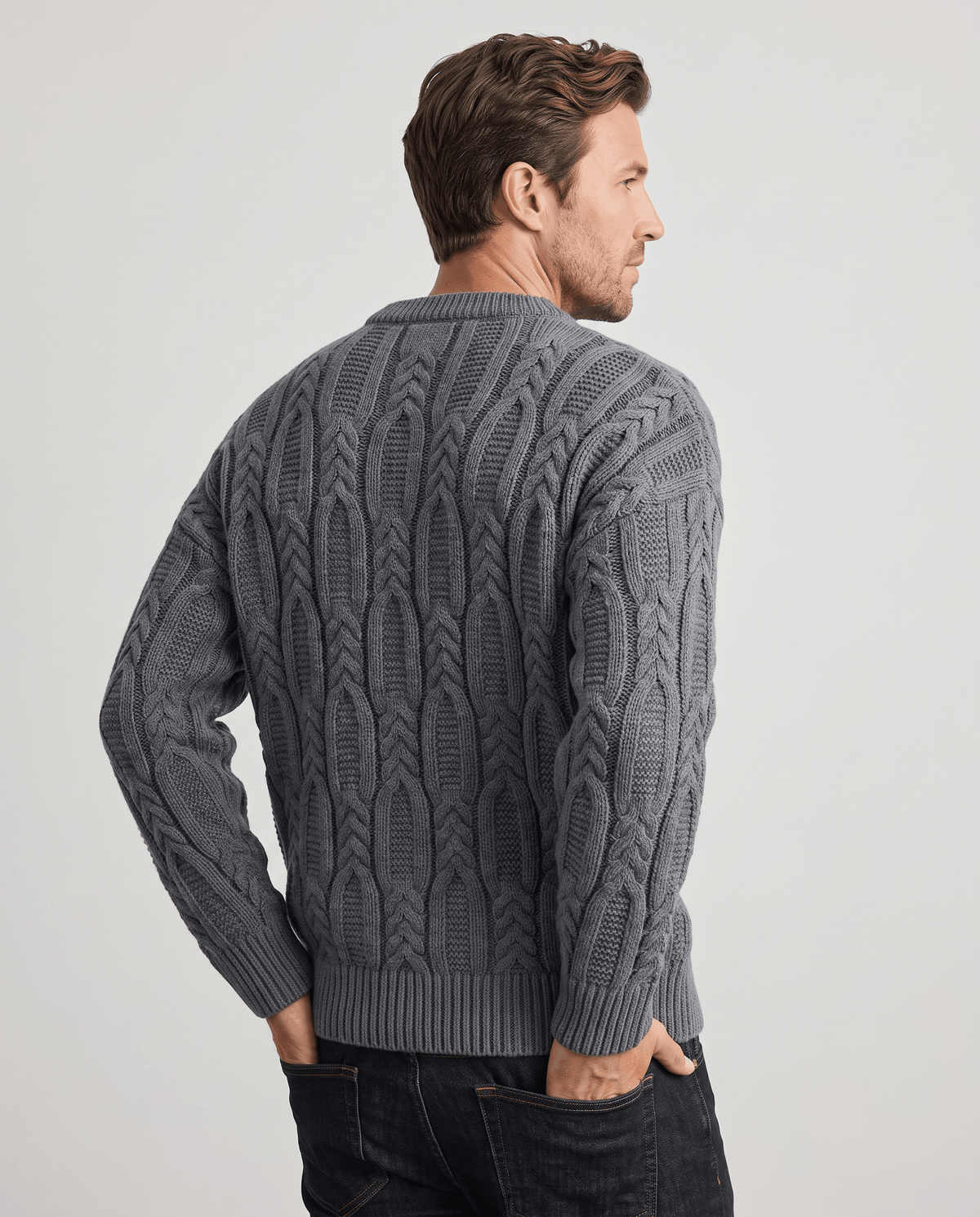 Back view of charcoal gray cable pullover with hands in pockets