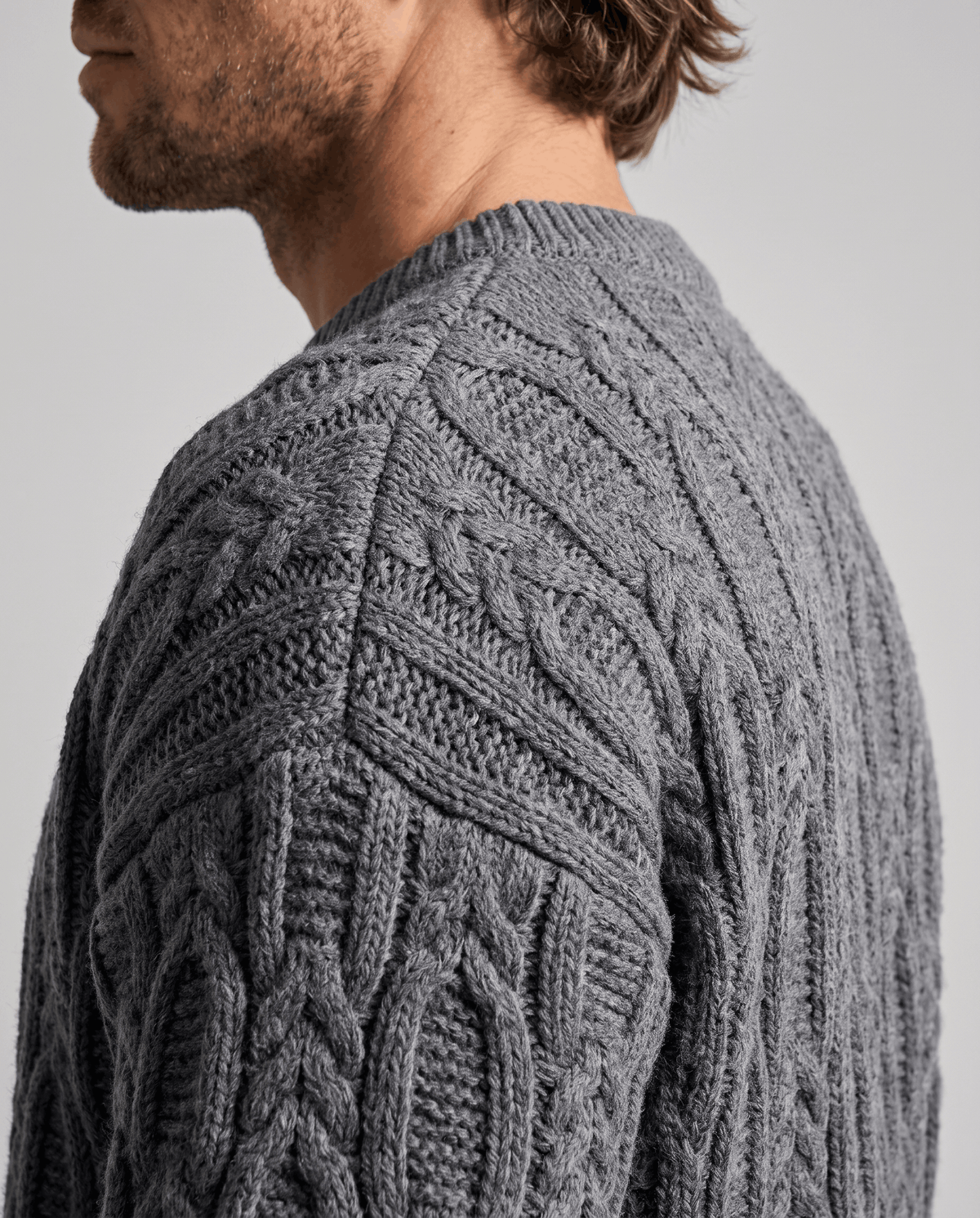Shoulder close-up of charcoal gray sweater showing braided cable texture
