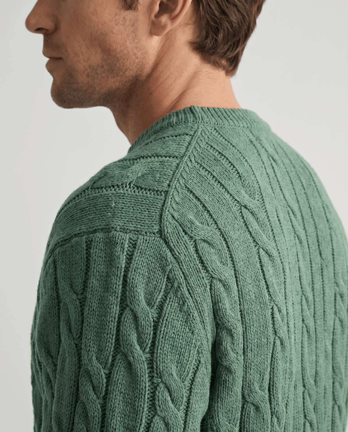 Side close-up of green sweater collar and shoulder cable stitching