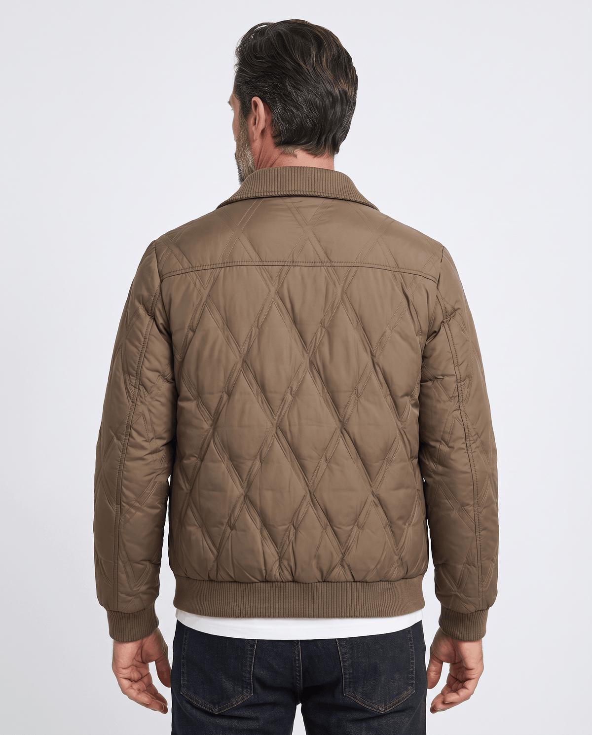Back view of a man wearing a brown diamond quilted puffer jacket with ribbed hem