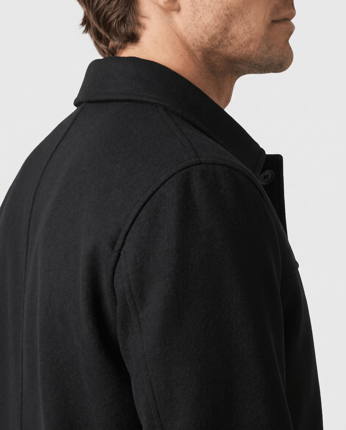 Black jacket shown in profile, sleeve and side seam in frame