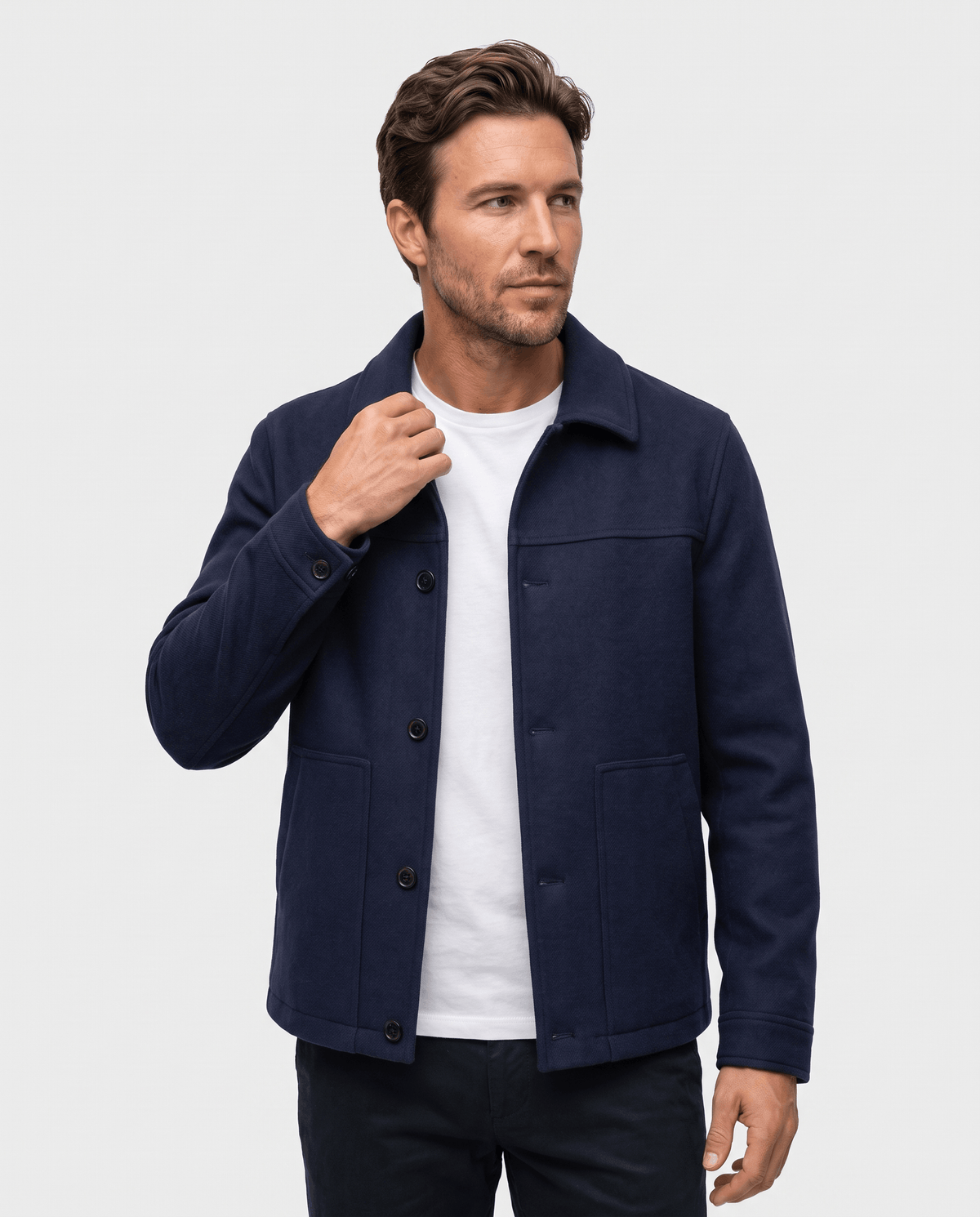 Navy jacket worn open over a dark knit, hand raised to the collar