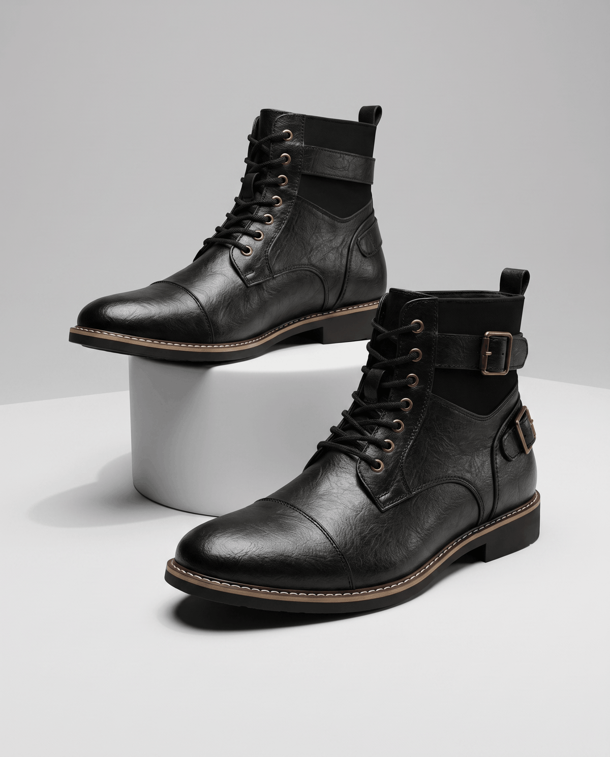 Black leather cap-toe lace-up boots featuring layered panels, adjustable buckle straps, and a welted stacked heel.