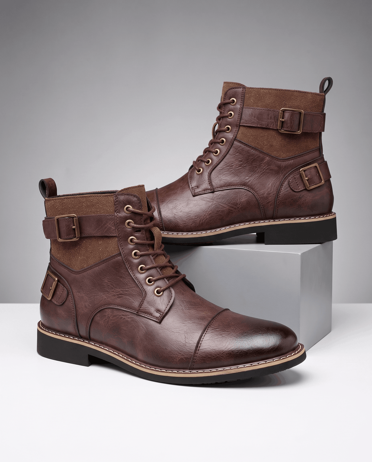 Burgundy cap-toe lace-up boots featuring layered panels, adjustable buckle straps, and a welted stacked heel.