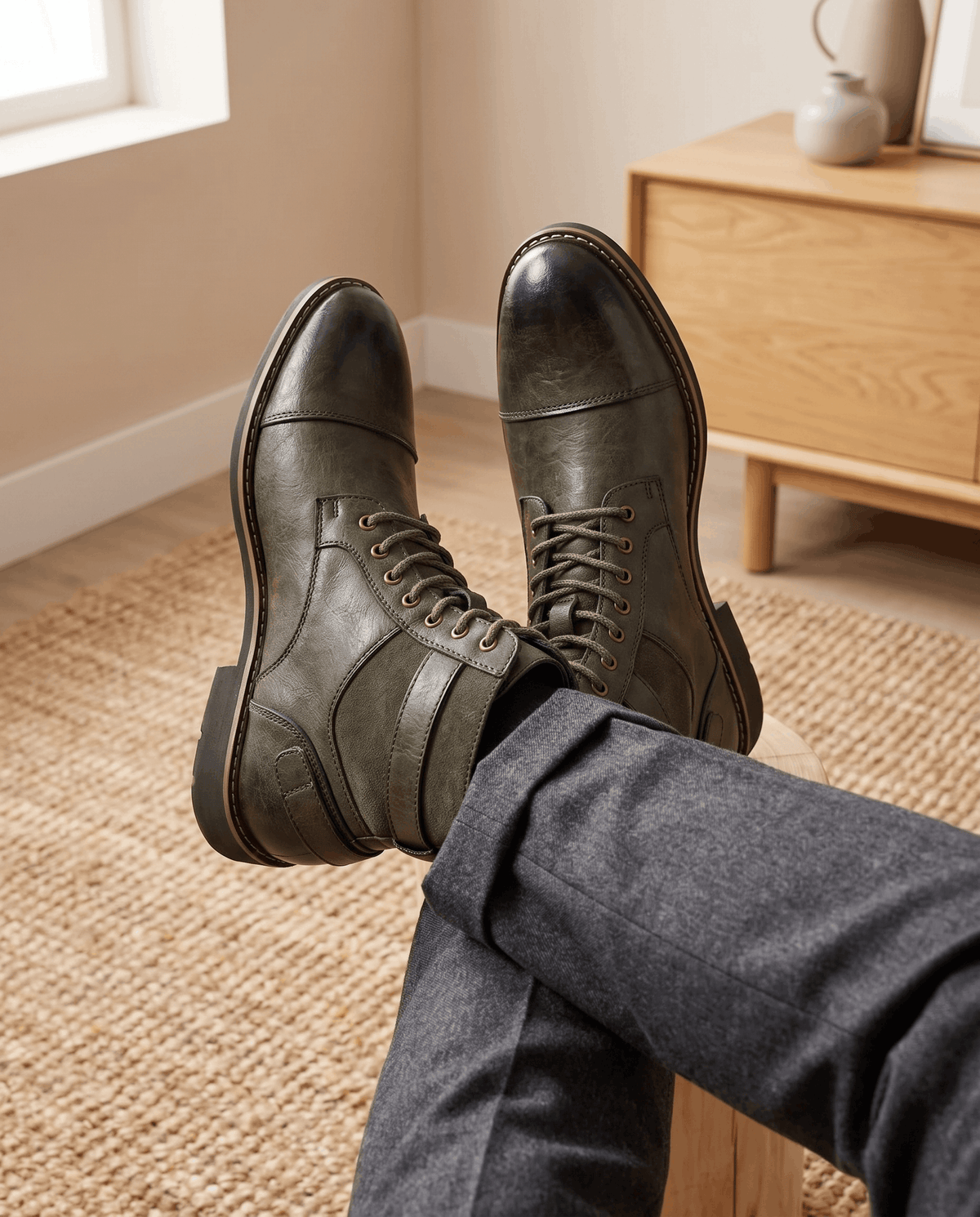 Olive green cap-toe lace-up boots with layered panels, adjustable buckle strap, and a welted stacked heel.