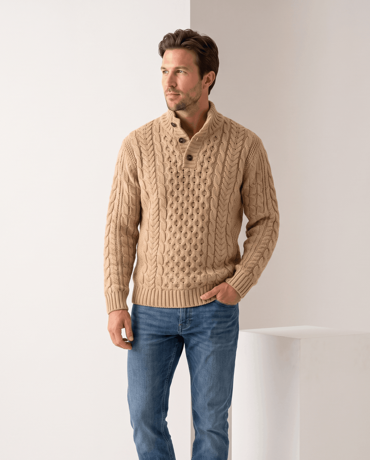Man wearing men's button mock neck cable-knit sweater in khaki with blue jeans