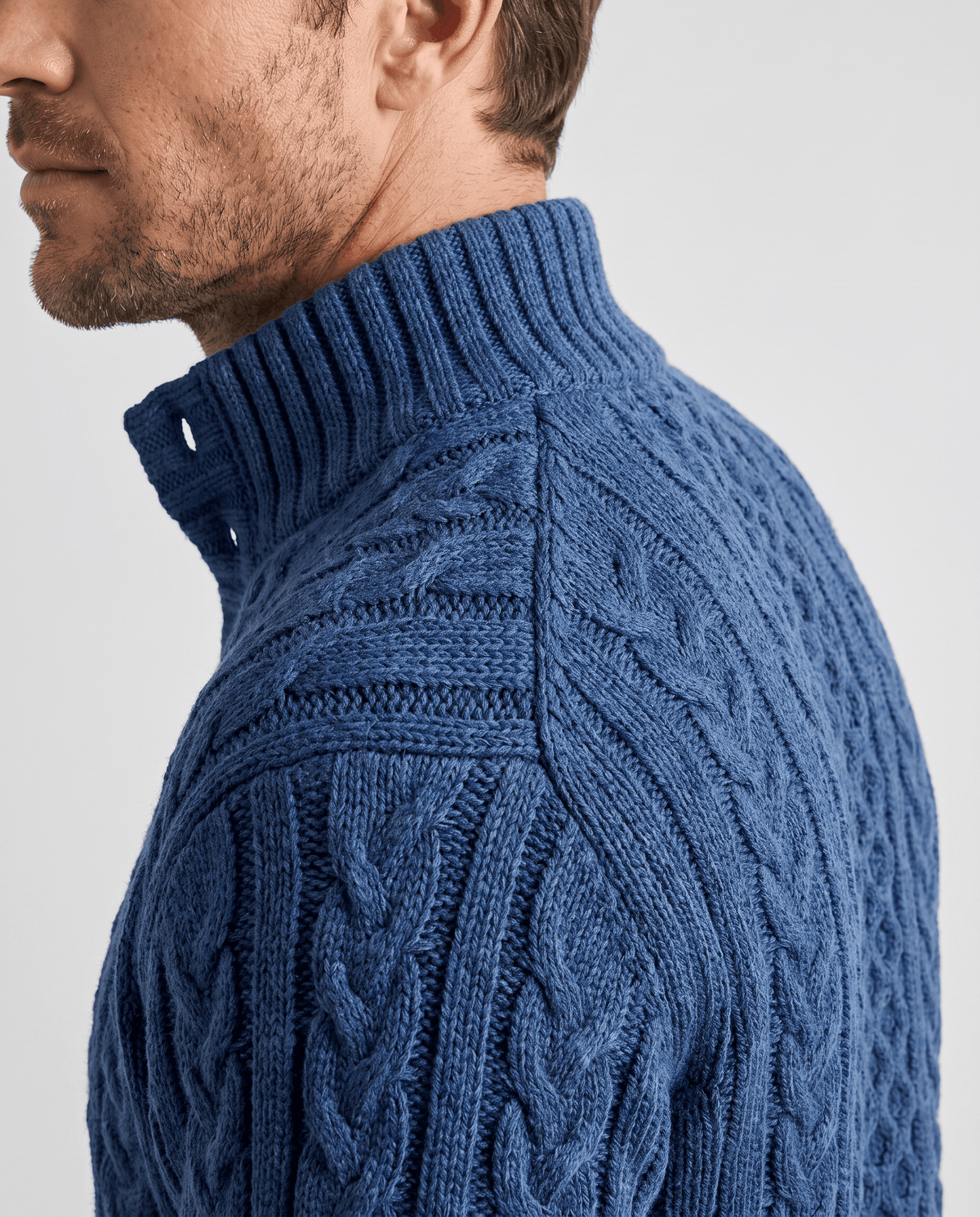Side close-up of navy ribbed collar and shoulder cable stitching