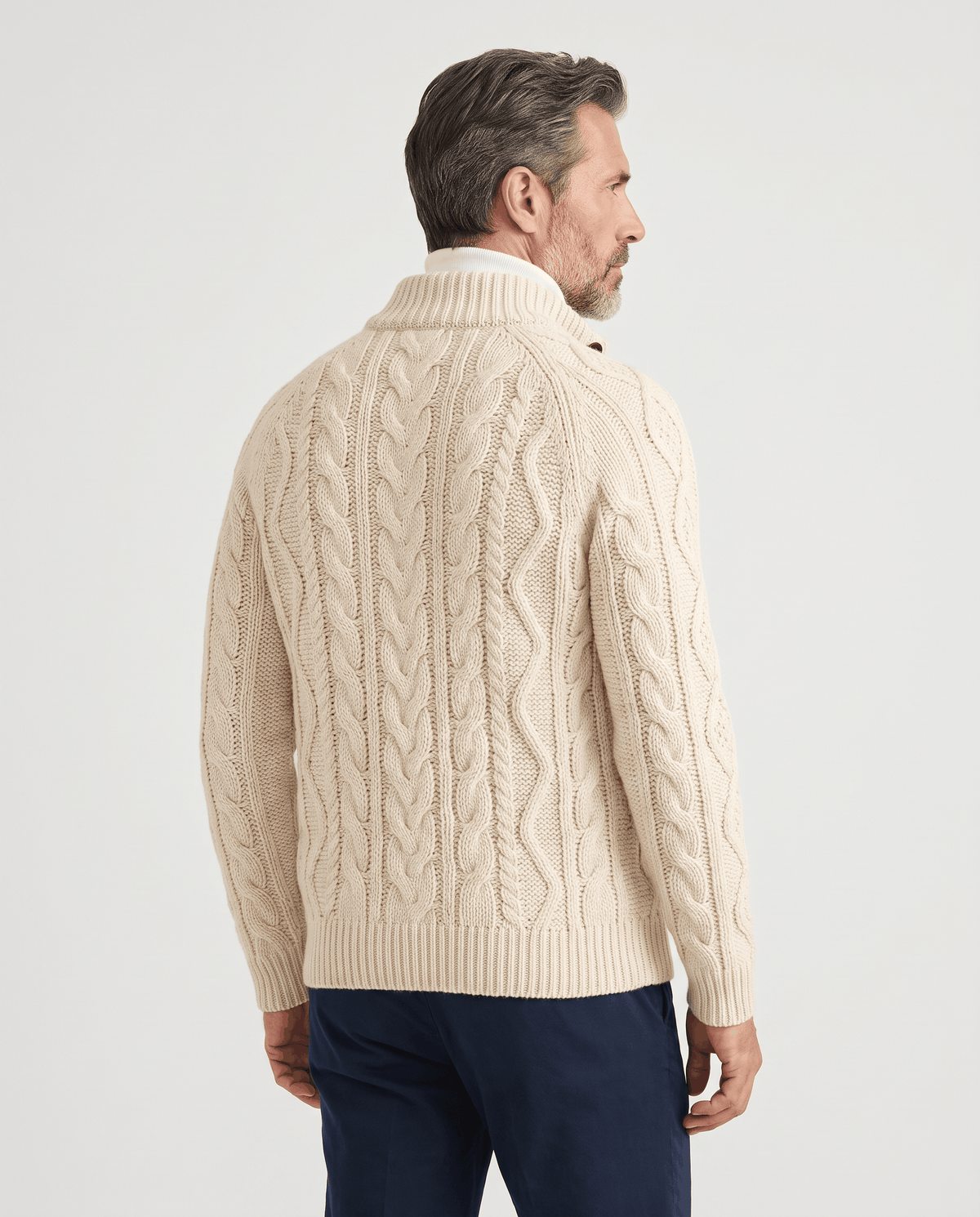 Back view of beige cable knit cardigan worn with blue jeans