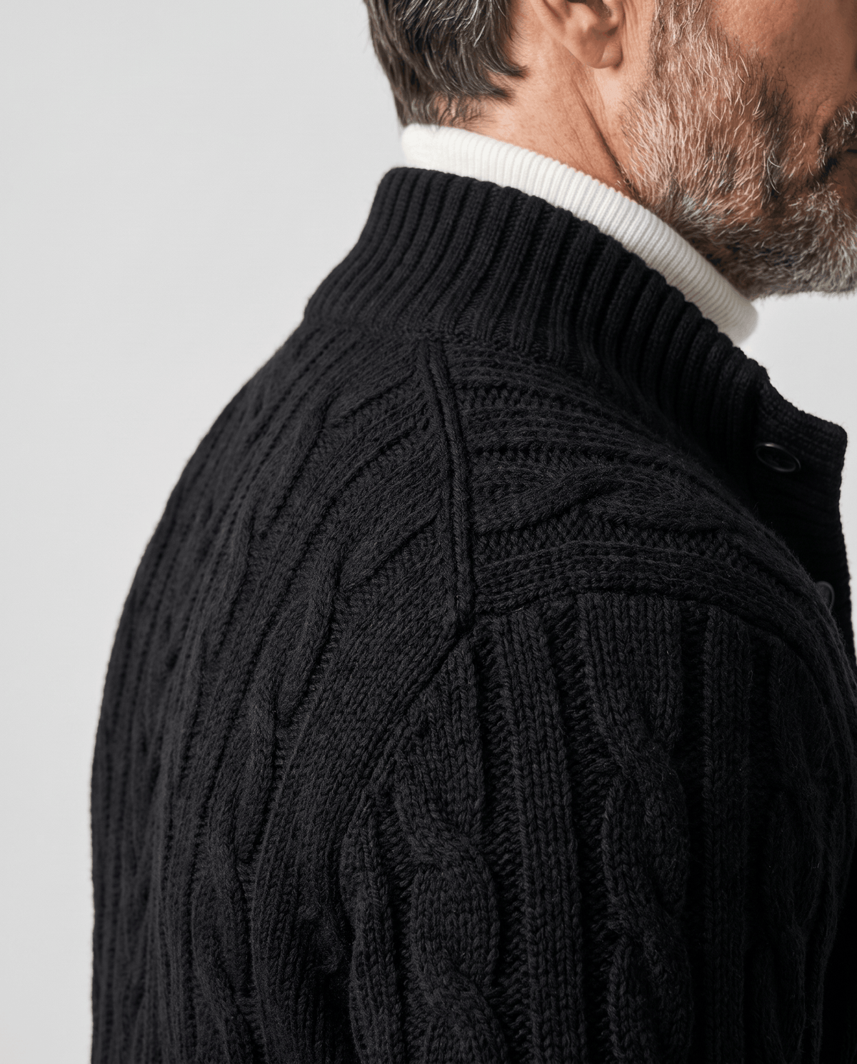 Close view of black cable knit cardigan stand collar and shoulder