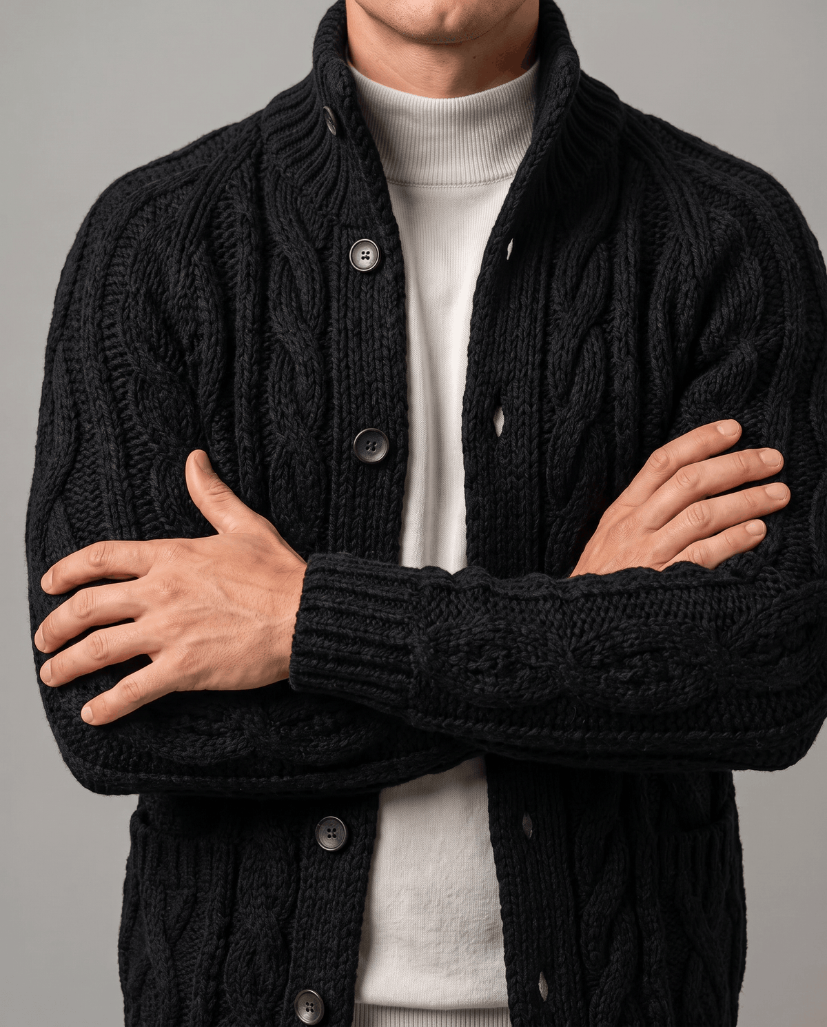 Black cardigan with arms crossed showing cable-knit texture and button front