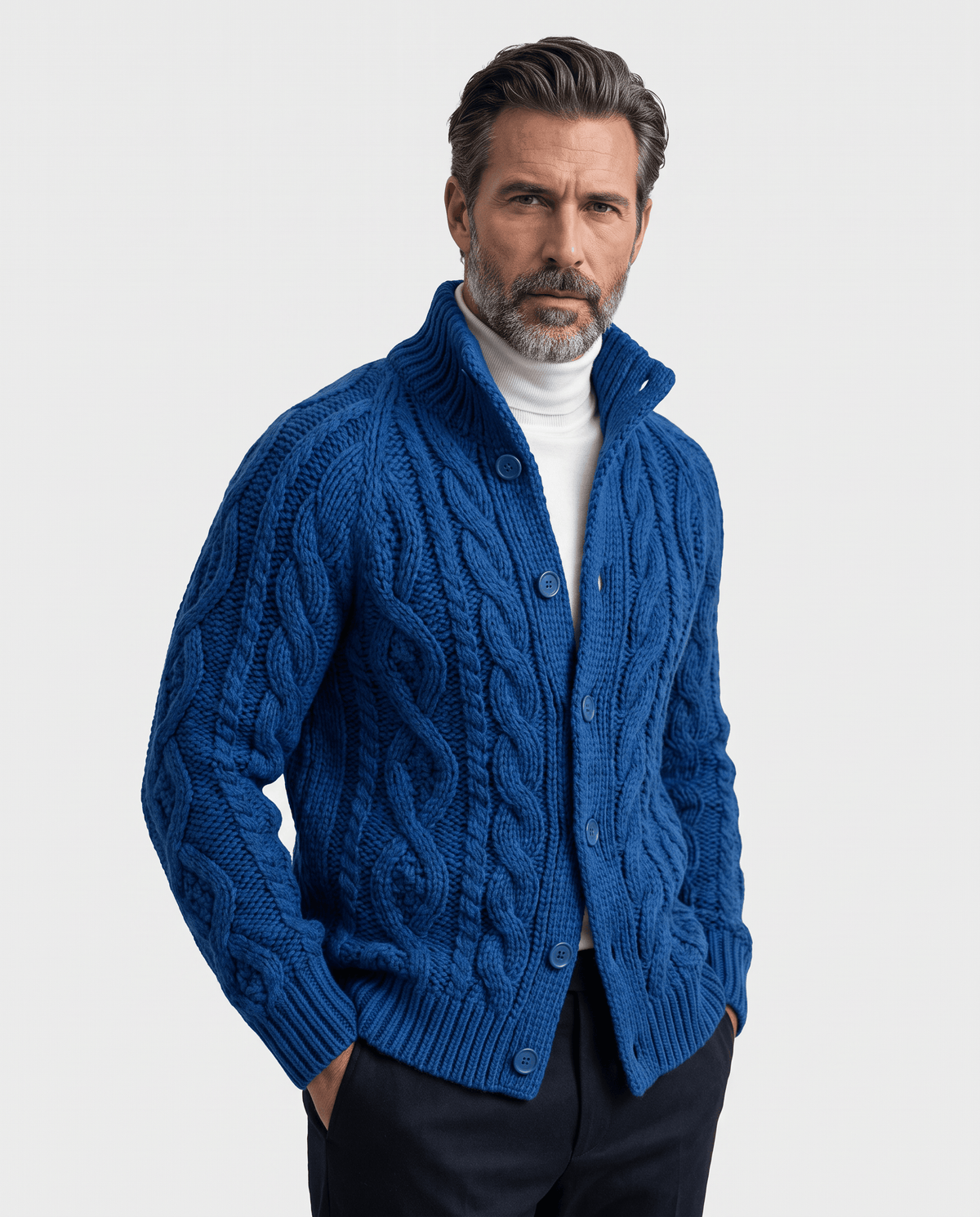 Men's blue cable knit cardigan with stand collar worn over a white turtleneck