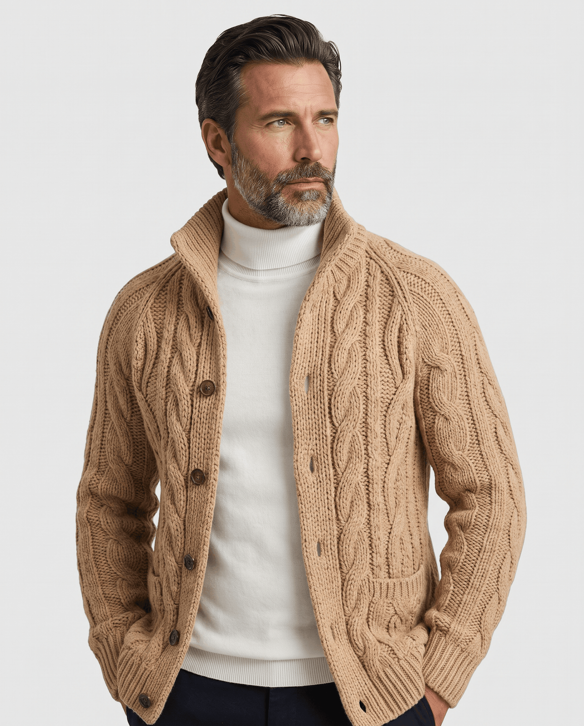 Men's light brown cable knit cardigan with stand collar worn over a white turtleneck