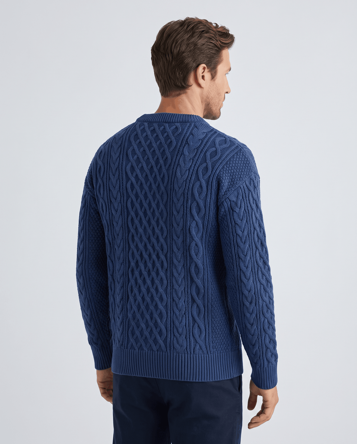 Back view of blue knit sweater showing cable columns and ribbed waistband