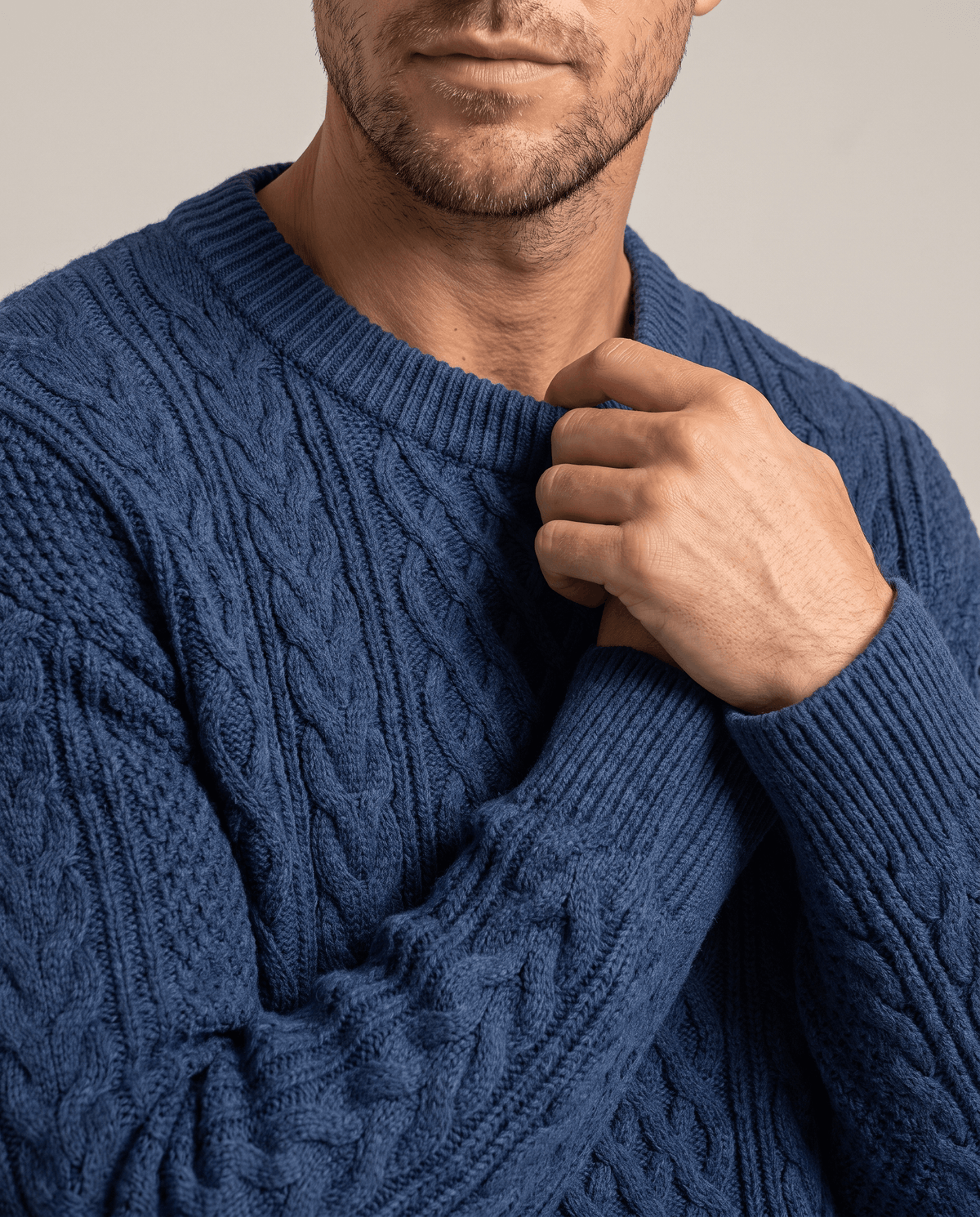 Close-up of hand at the ribbed collar of a blue cable sweater