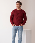 Man wearing men's chunky cable-knit crew neck sweater in burgundy with light jeans