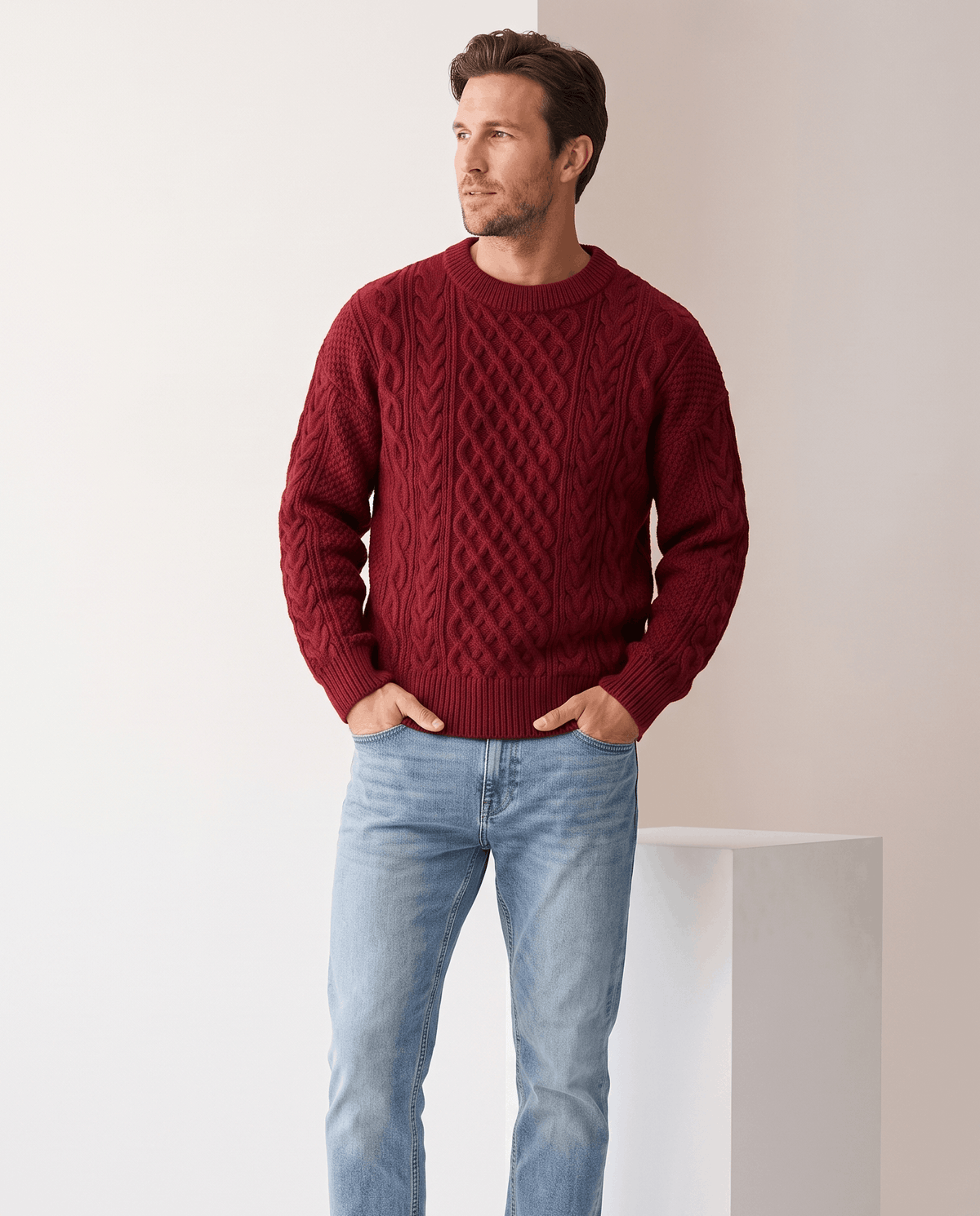 Man wearing men's chunky cable-knit crew neck sweater in burgundy with light jeans