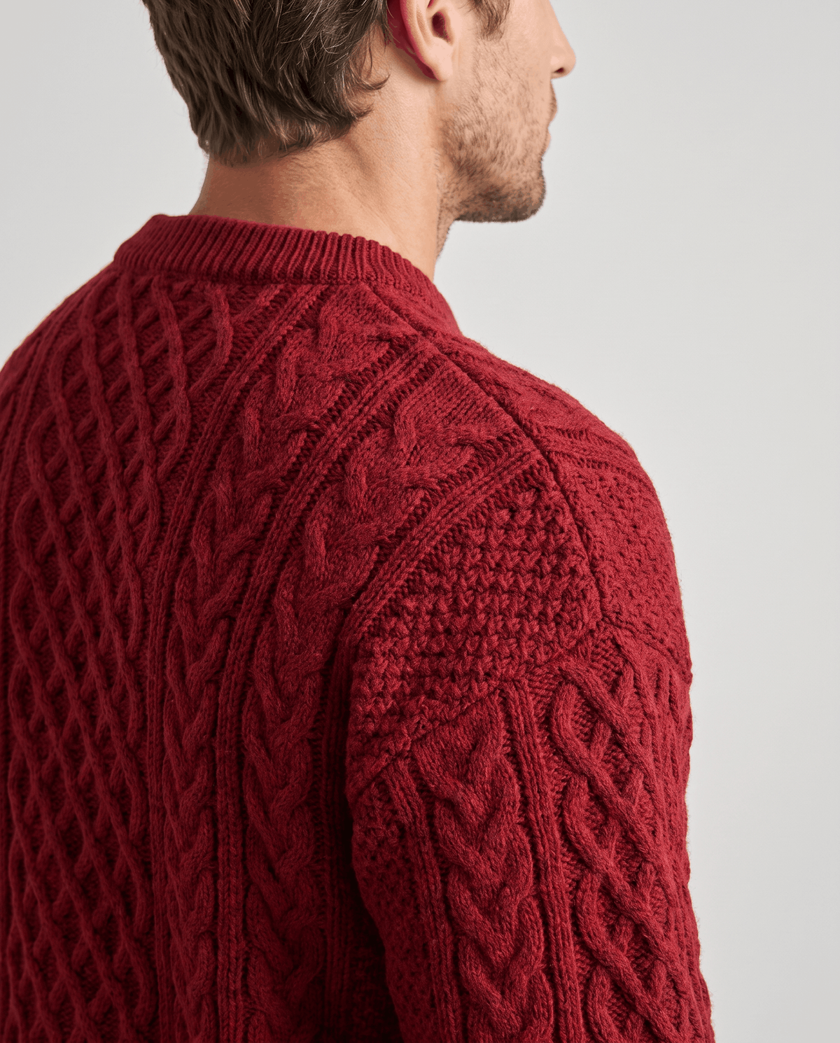 Close-up of burgundy crew collar and shoulder showing twisted rope cable stitching