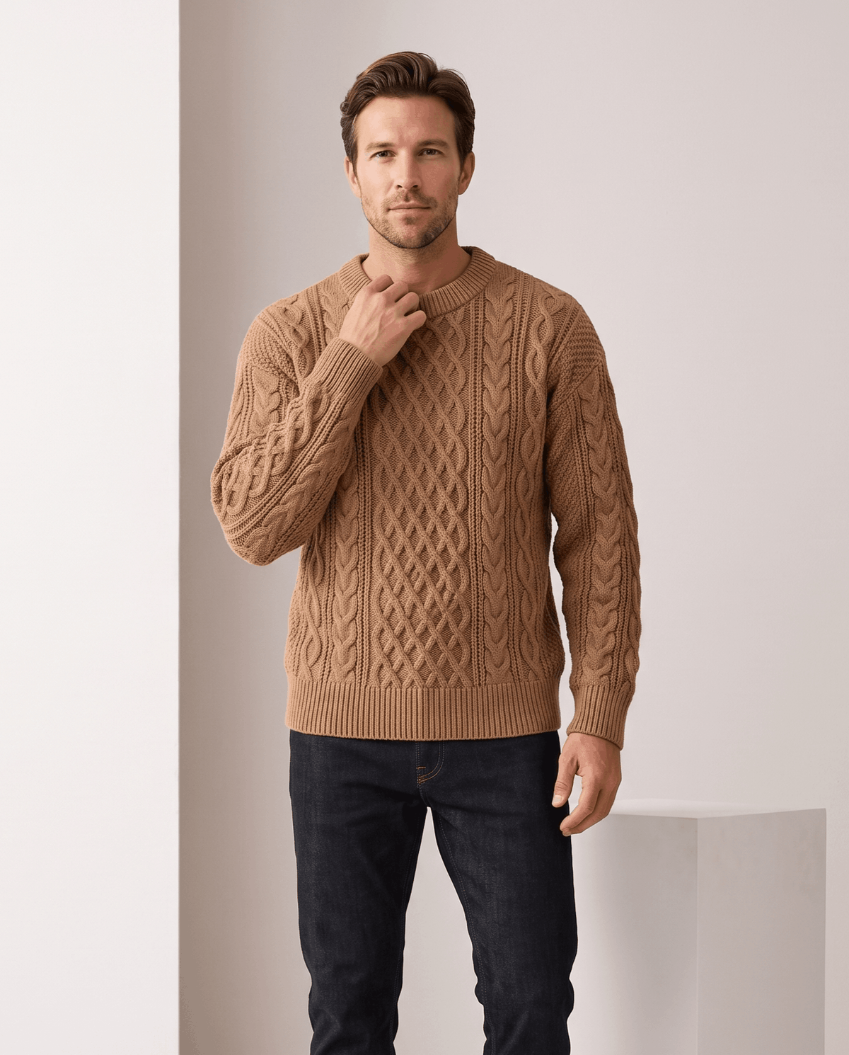 Model in camel crew neck sweater with black trousers beside a white plinth