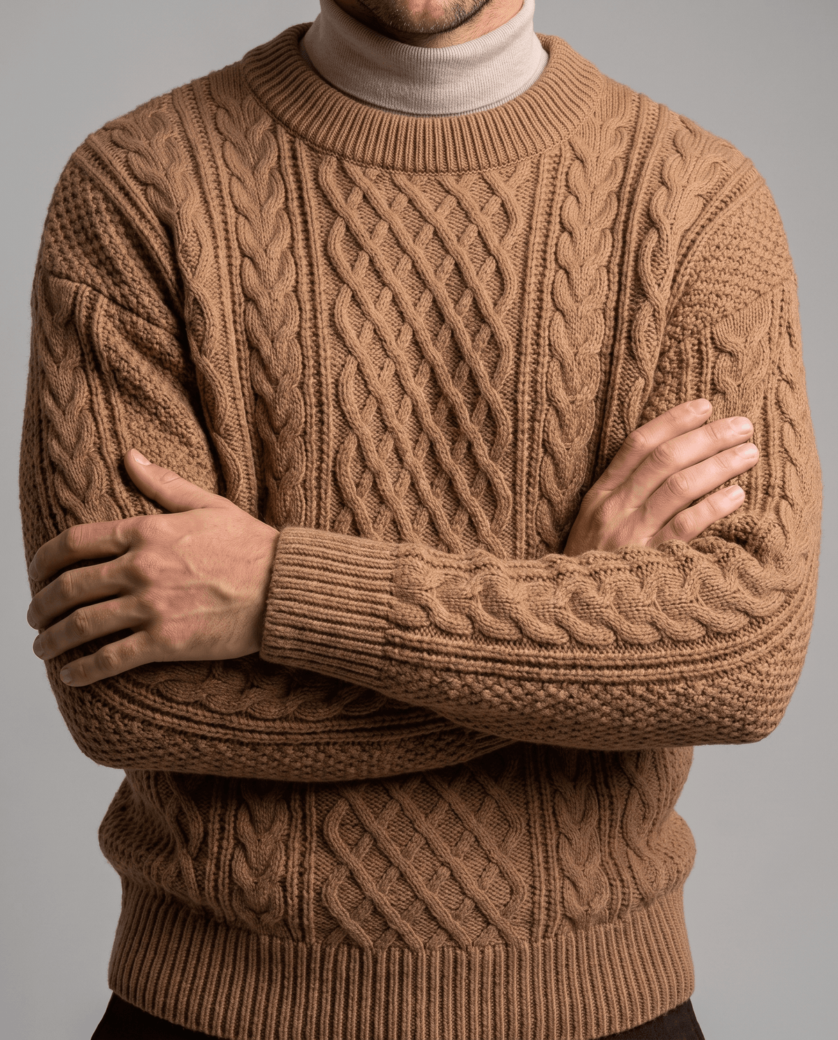Camel cable knit worn over cream mock neck with arms folded