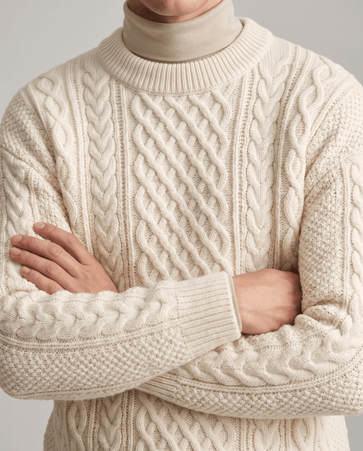Cream chunky knit over beige mock neck with arms crossed showing seed stitch cuffs