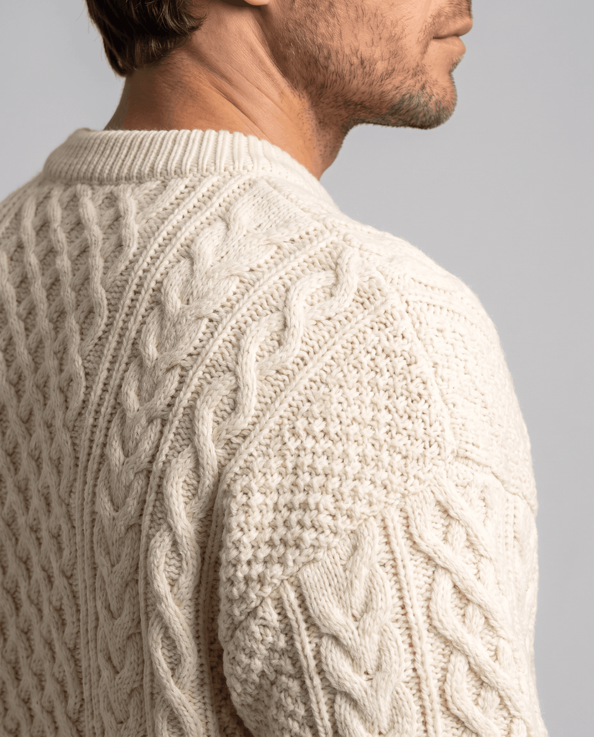 Shoulder and collar close-up of cream sweater with raised rope cables