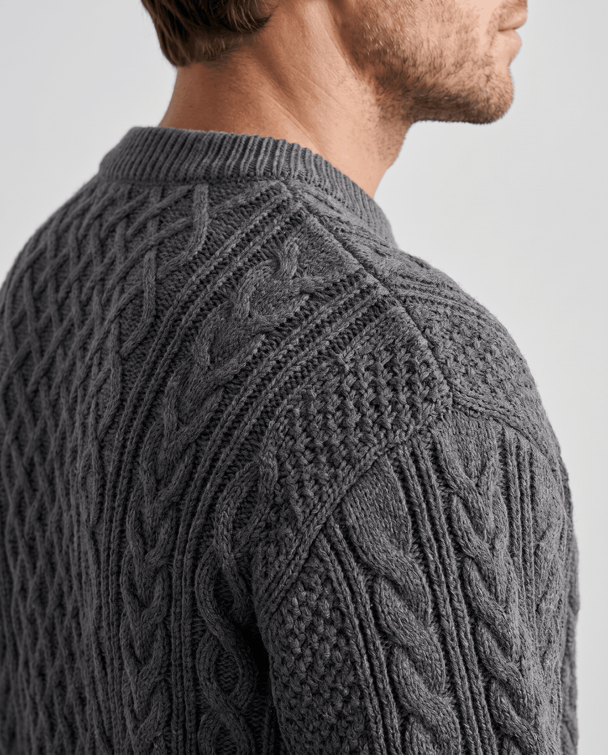 Shoulder close-up of charcoal gray sweater with seed stitch and rope cables