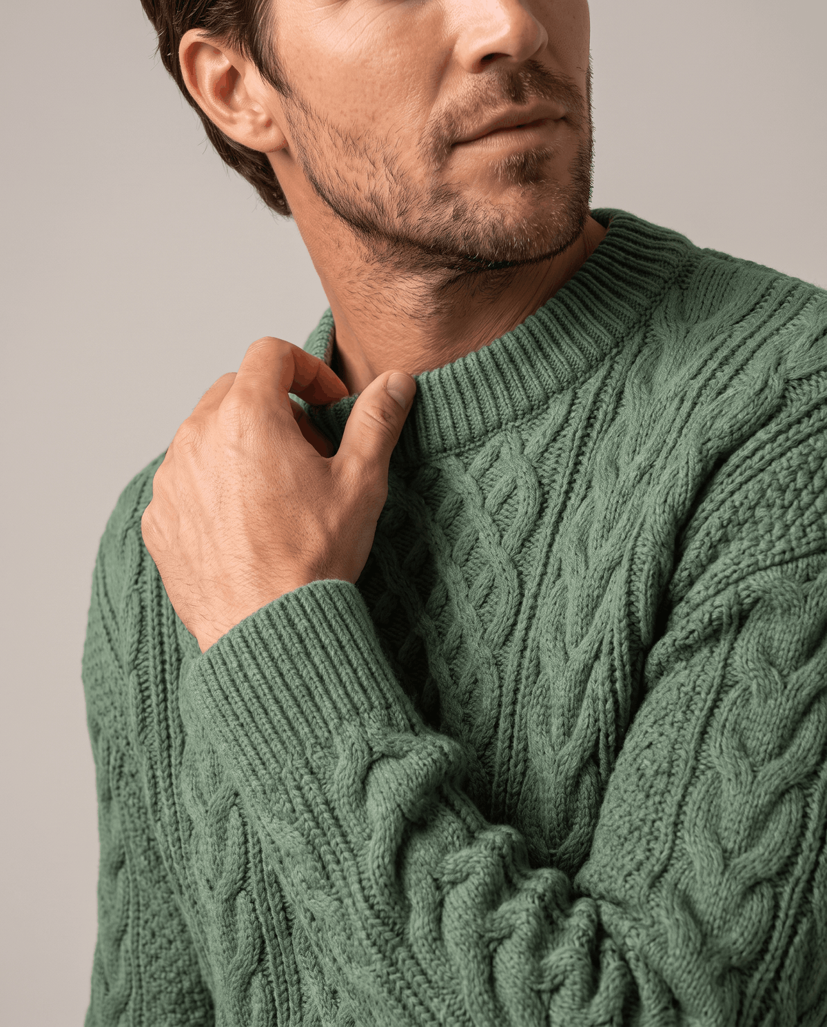 Three-quarter view of sage green knit showing collar rib and sleeve cables
