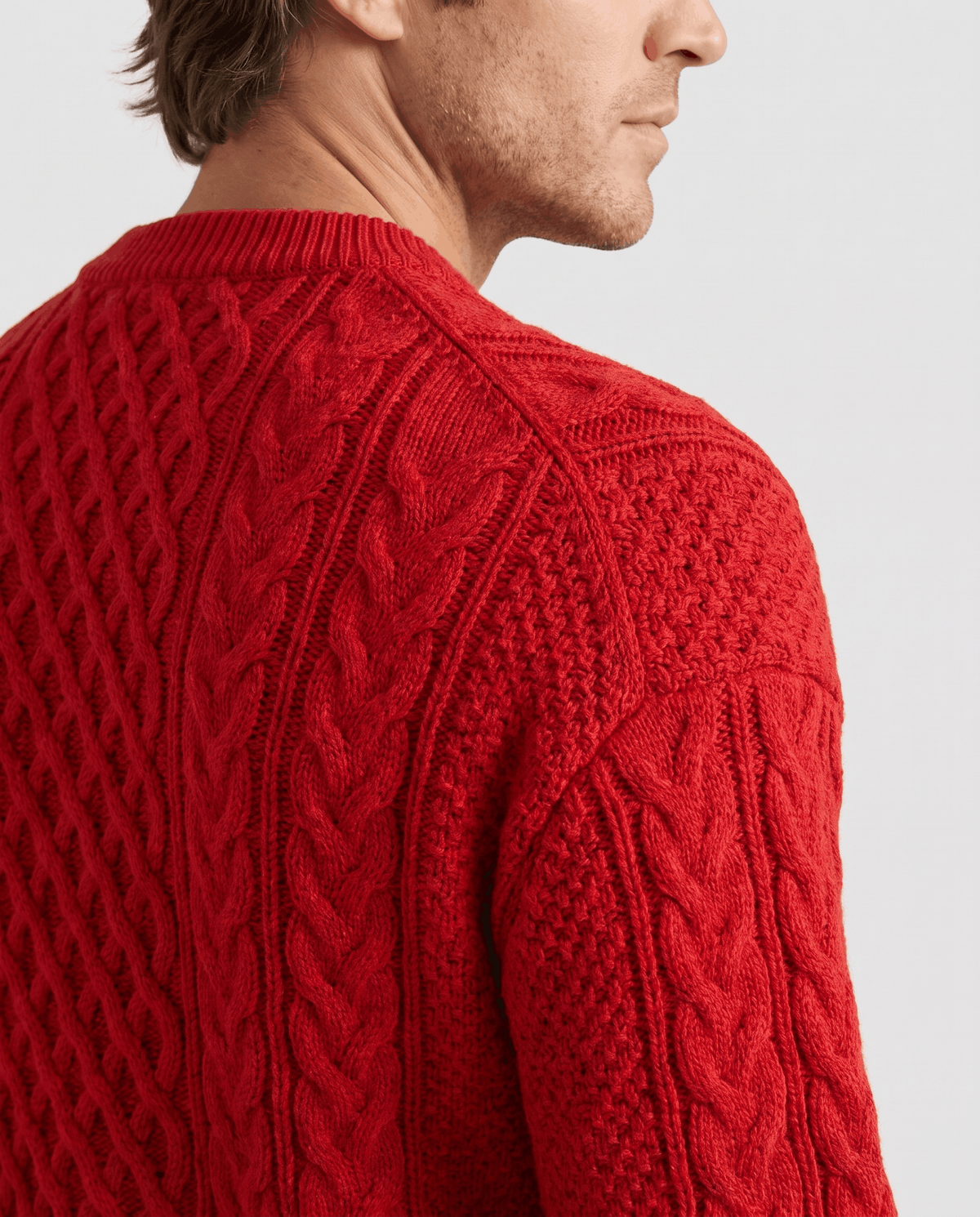 Side close-up of bright red sweater collar and shoulder cable stitching