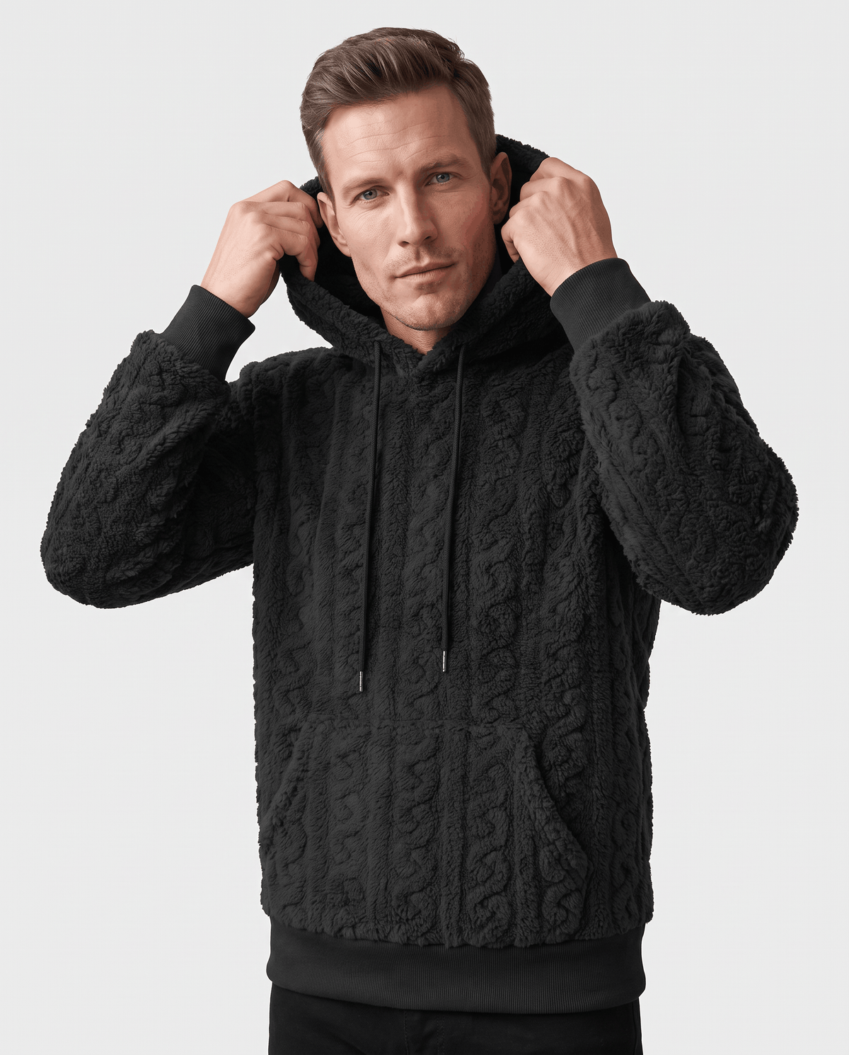 Front view of black hoodie with hands raised to the hood and drawstrings hanging