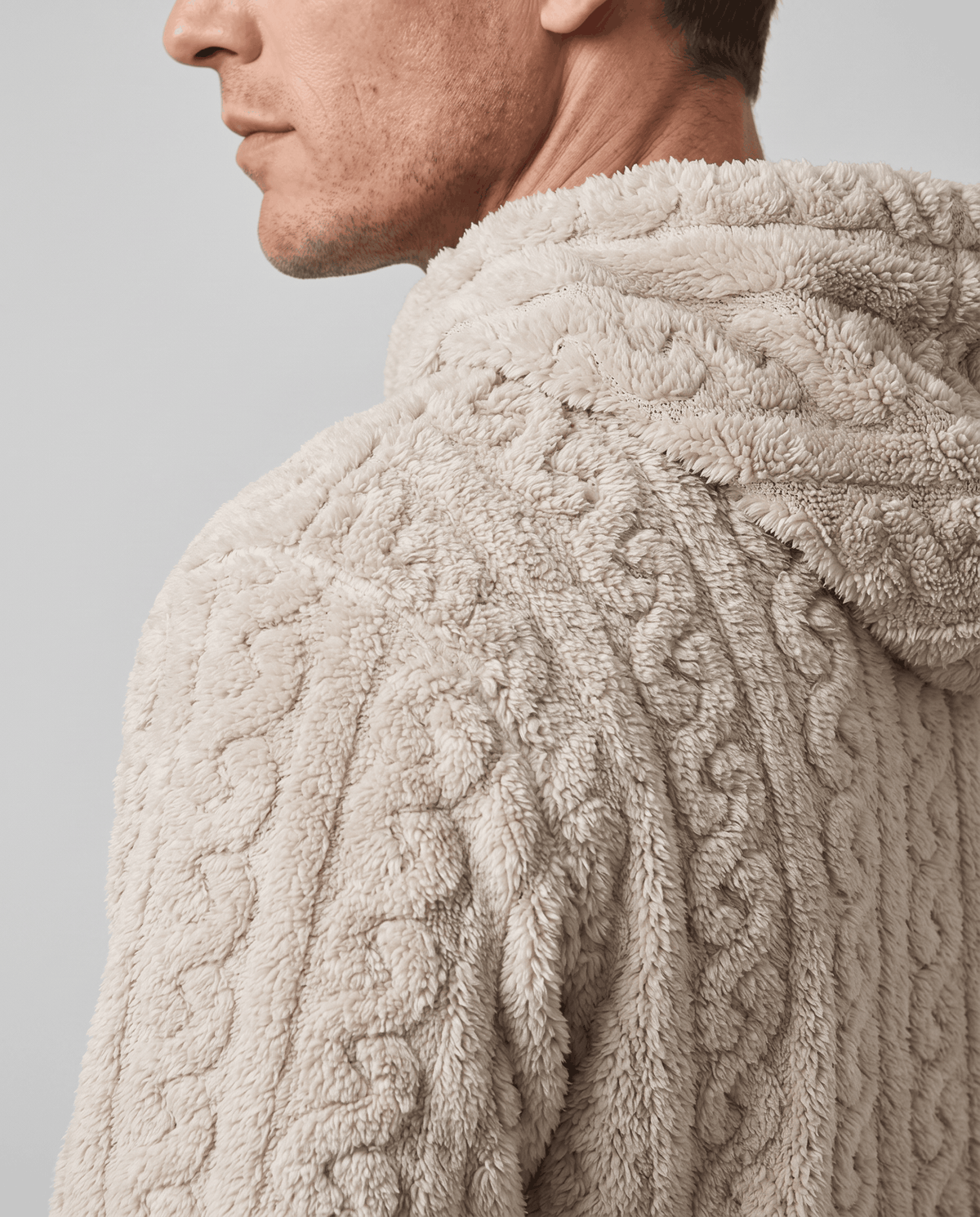 Side close-up of off-white hood and shoulder showing the chunky cable pattern